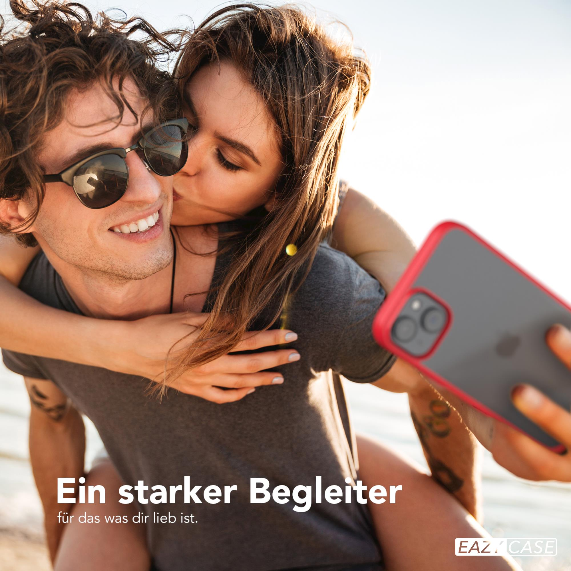 Ein Paar macht ein Selfie. Die Frau küsst den Mann. Der Mann hält ein Telefon mit roter Hülle.