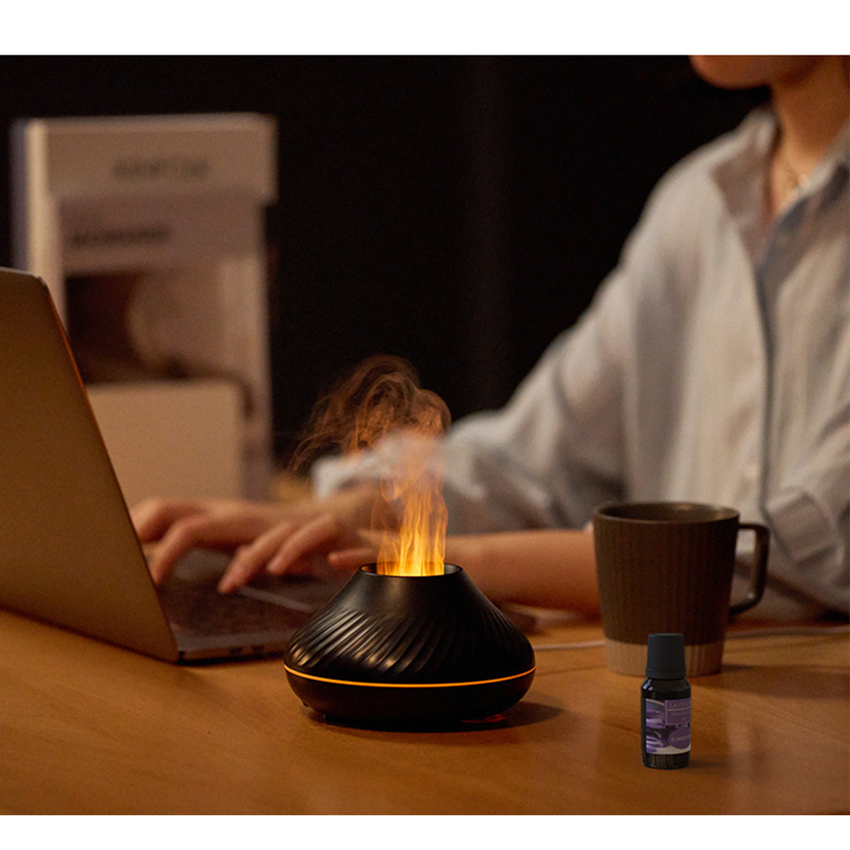 Aromadiffusor, der Flammen ausstößt. Frau arbeitet im Hintergrund an einem Laptop.