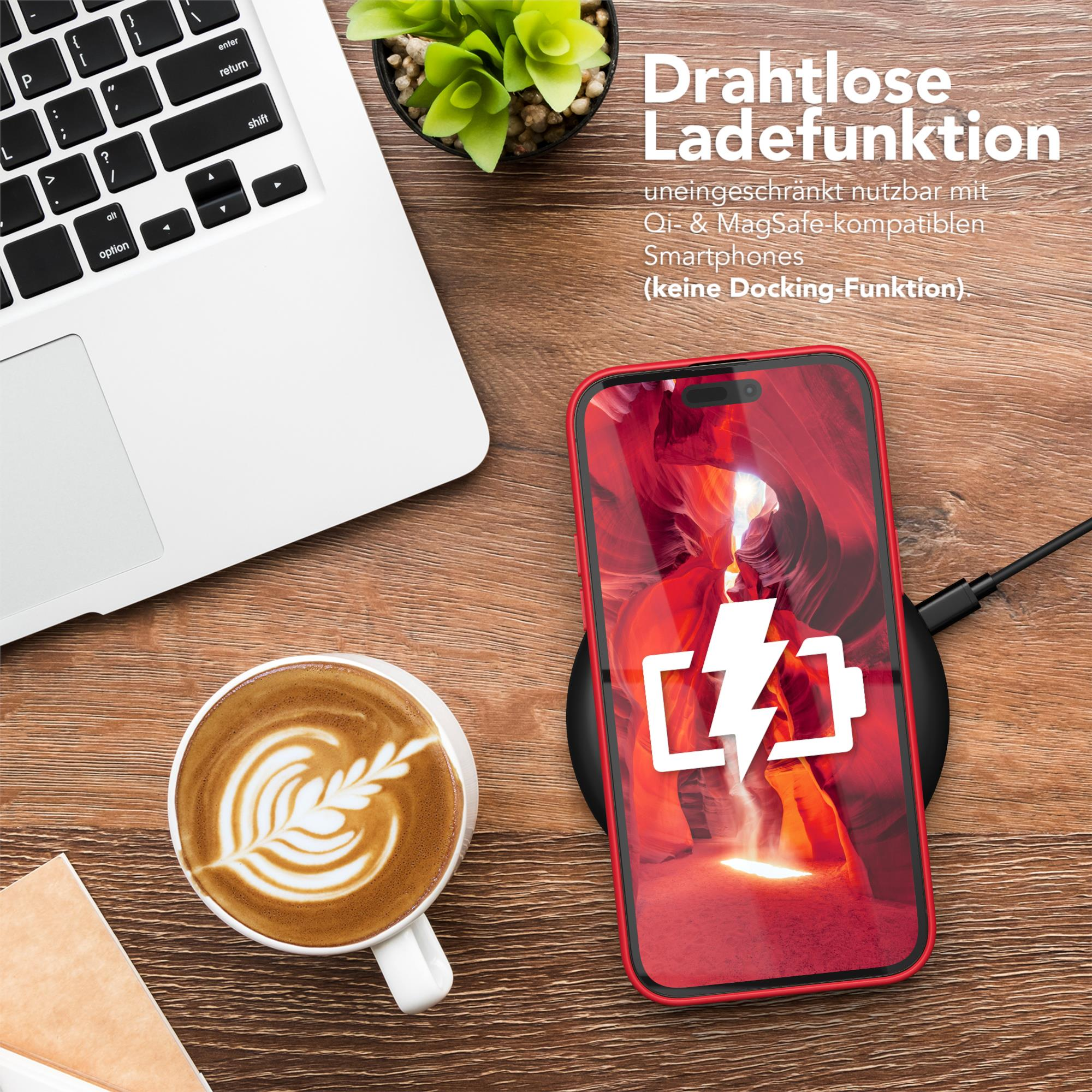 Ein Telefon, das drahtlos auf einem schwarzen Pad geladen wird. Daneben eine Kaffeetasse mit Latte Art und ein Laptop.