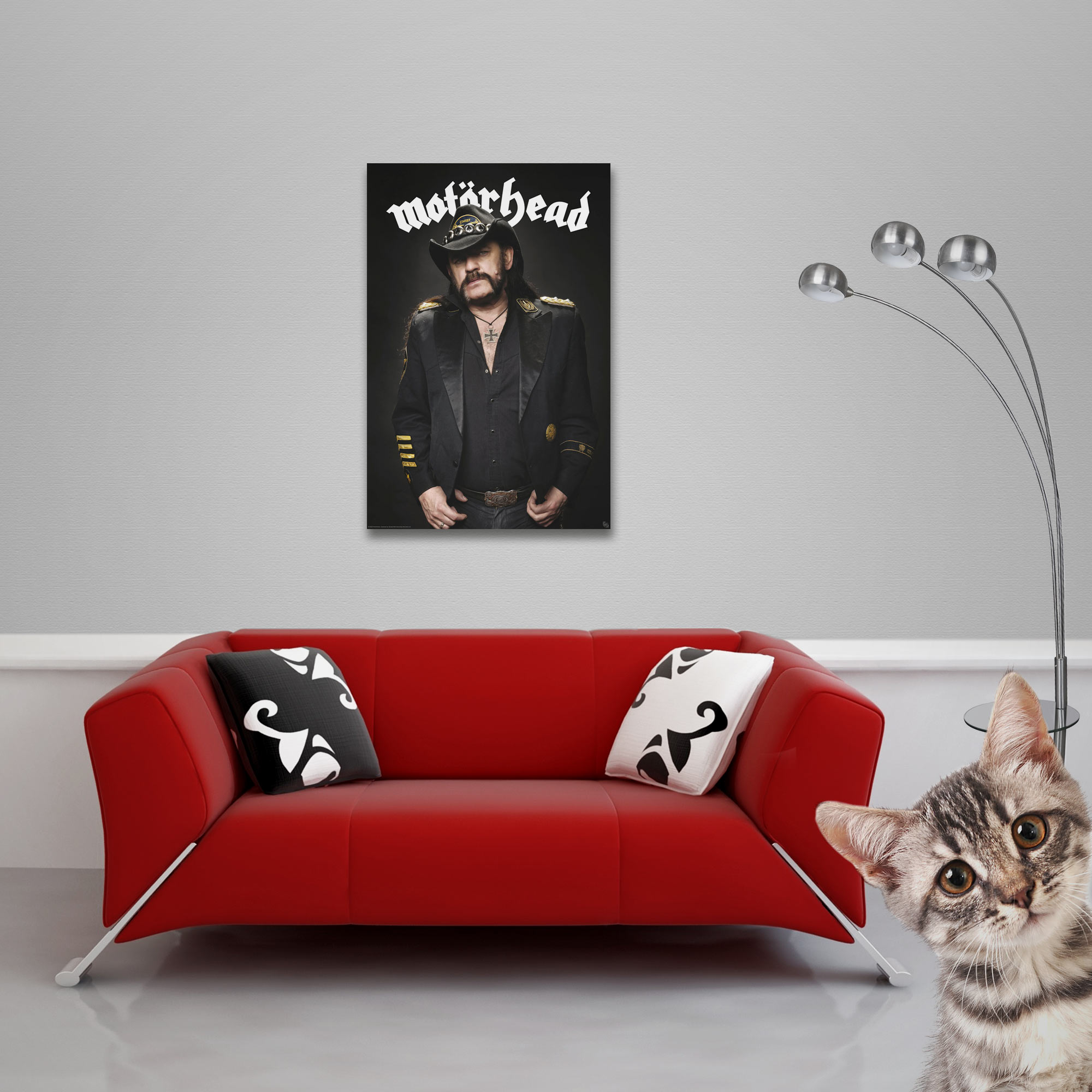 Ein Poster von Motörhead, ein rotes Sofa, eine Katze und eine Lampe.