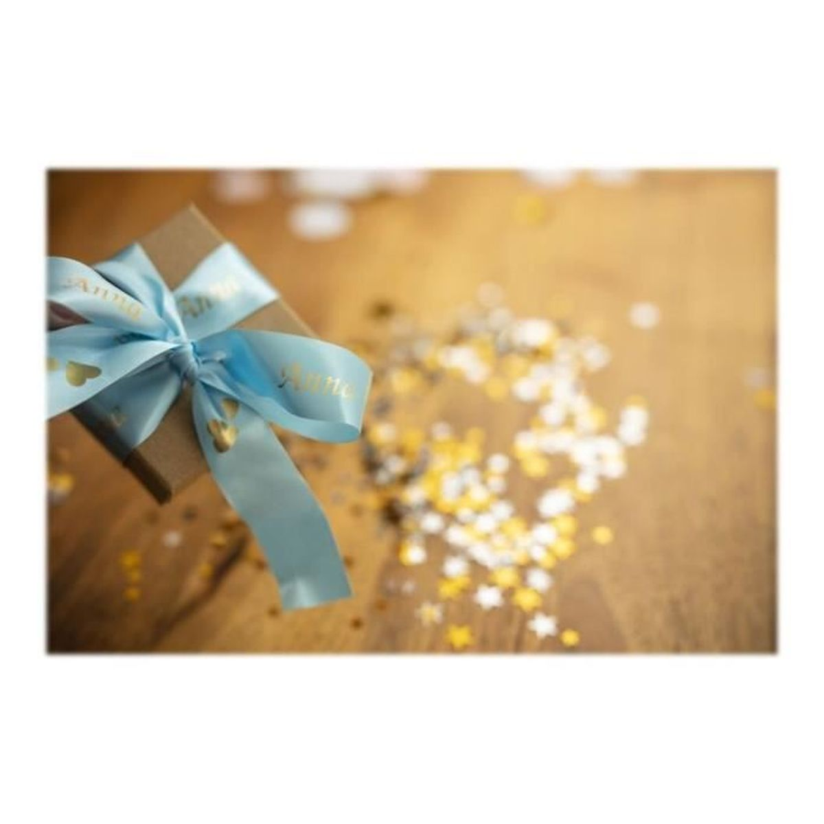 Eine Geschenkbox mit blauem Band und Schleife. Streuendes goldenes Konfetti auf Holzoberfläche.