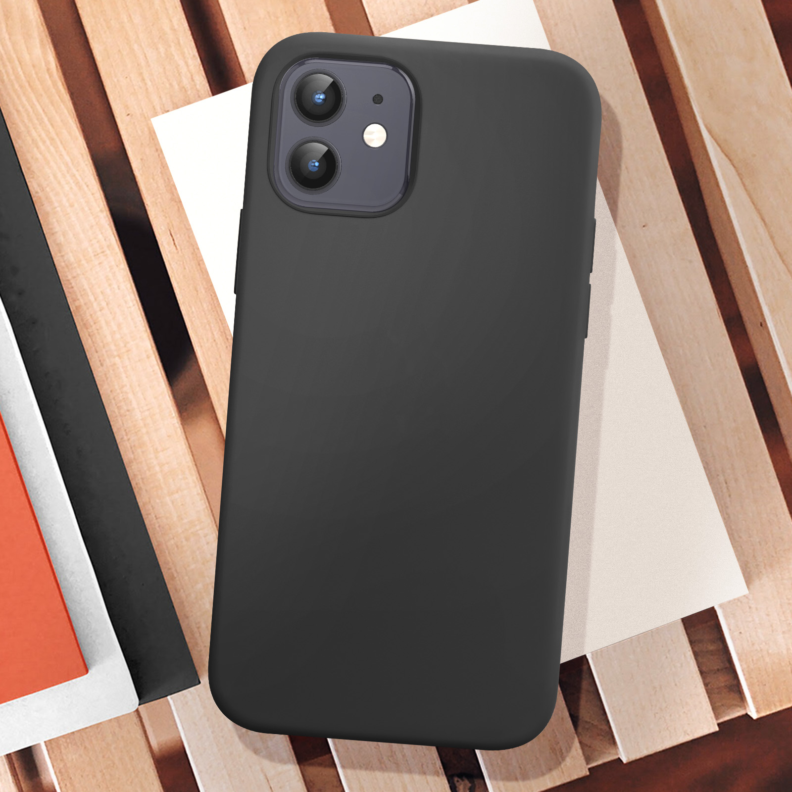 iPhone nero con custodia nera su superficie in legno. Fogli bianchi e arancioni sotto il telefono.