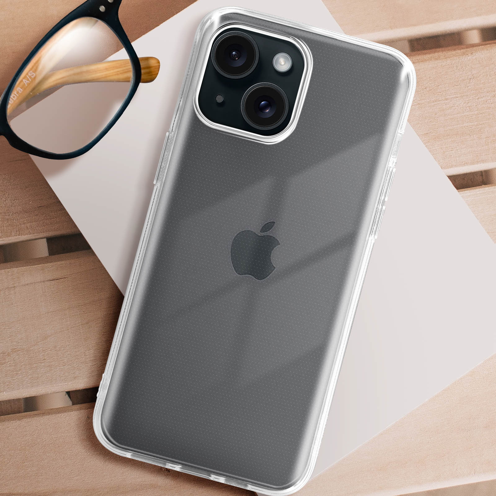 Una custodia trasparente per telefono su un tavolo di legno, con un telefono all'interno, occhiali e uno sfondo neutro.