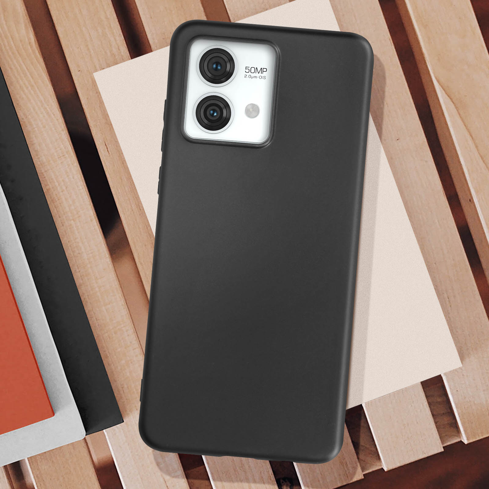 Custodia nera per telefono su superficie in legno, con telefono e fotocamera visibili.