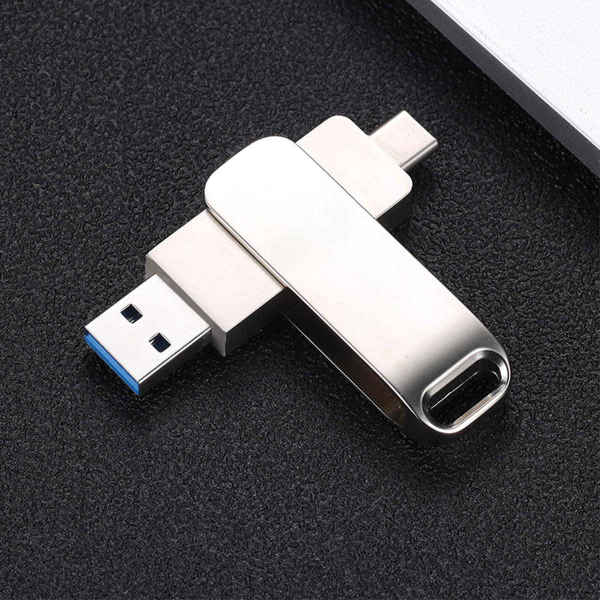 Ein silberner USB-Stick mit einem USB- und einem USB-C-Anschluss auf einer schwarzen Oberfläche. Der USB-Anschluss hat einen blauen Akzent.