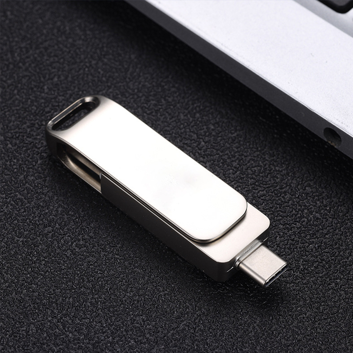 Silberner USB-C-Stick. Metall-Finish. Auf dunkler Oberfläche, möglicherweise einem Schreibtisch oder Tisch.