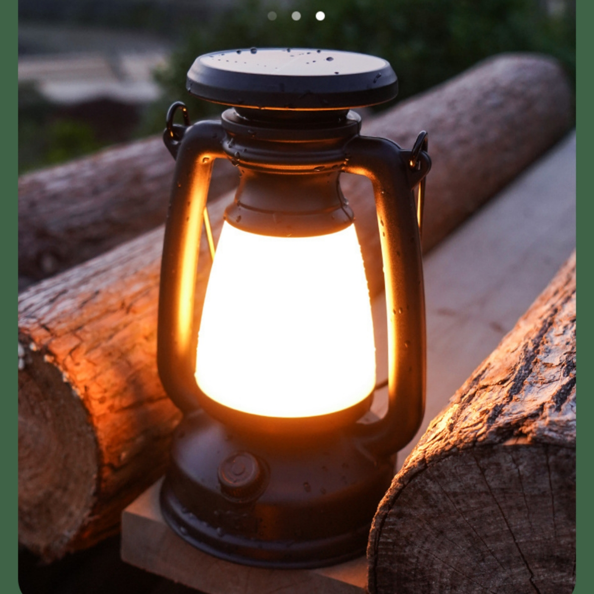 Laternenförmige Lampe, schwarz mit hellem weißem Licht. Umgeben von Holzscheiten. Der Hintergrund ist dunkel.