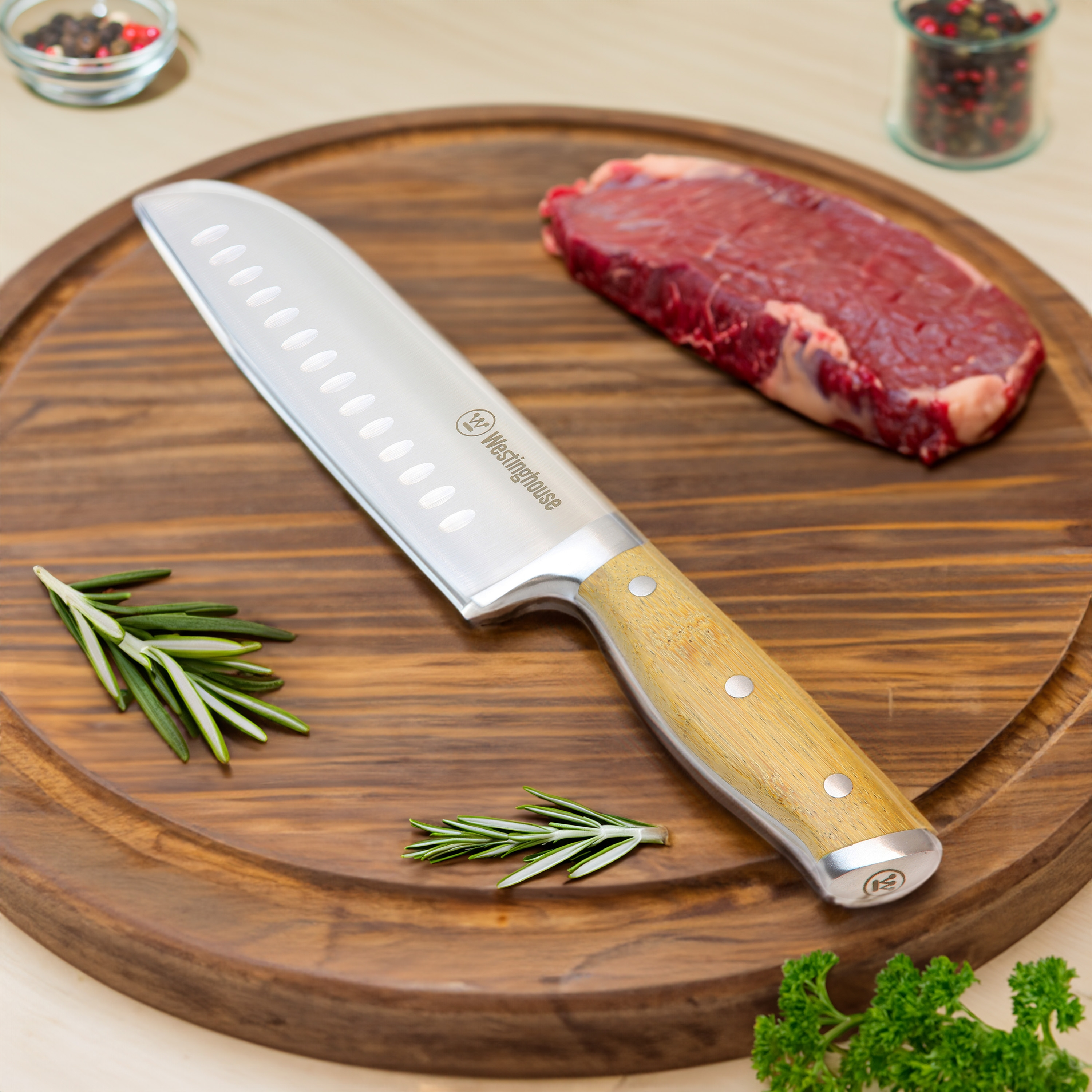 Ein Kochmesser auf einem Holzbrett. Steak und Rosmarinzweige liegen daneben.