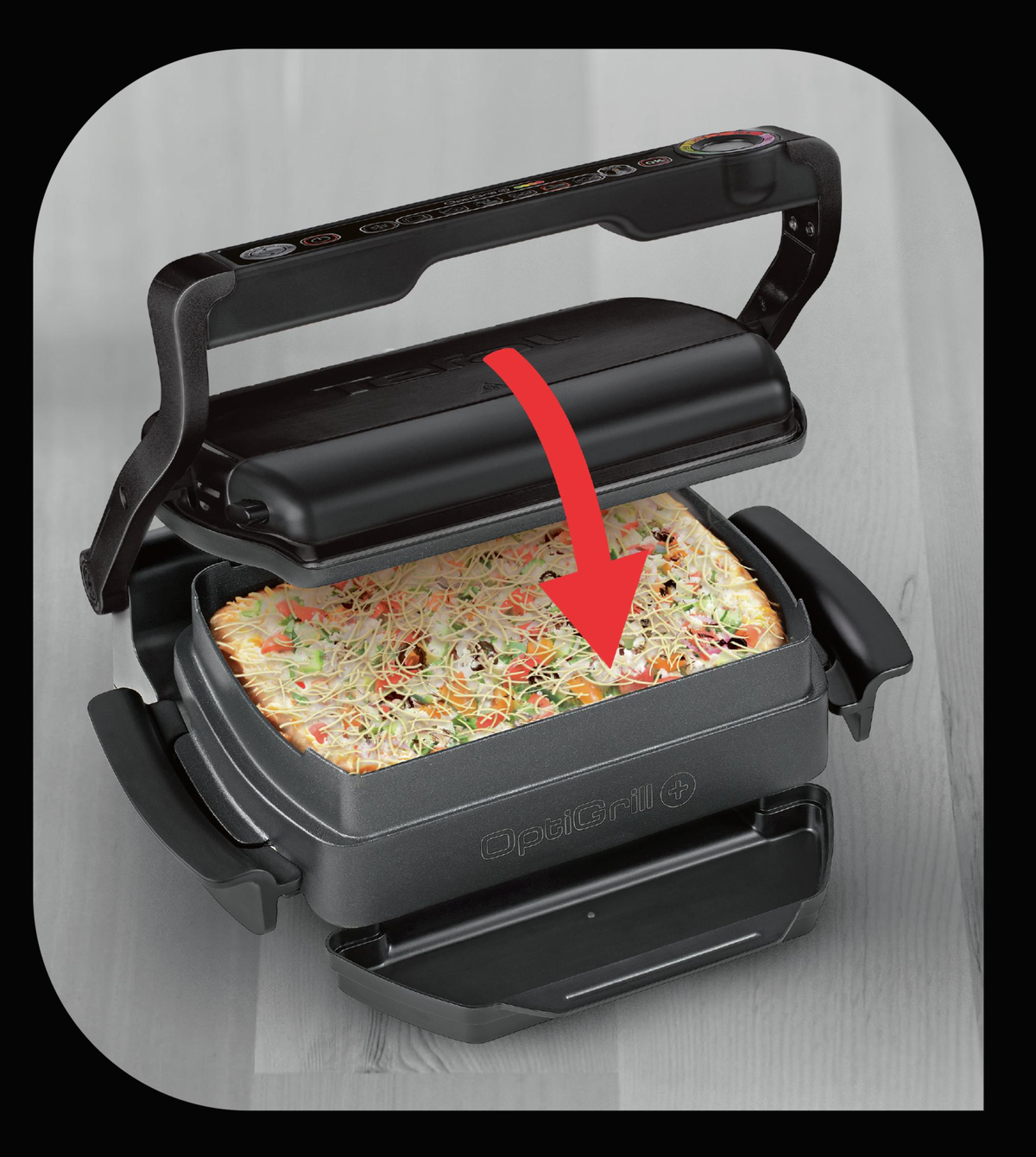 OptiGrill nero. Coperchio aperto. Una pizza all'interno. Una freccia rossa indica la pizza. Superficie nera.