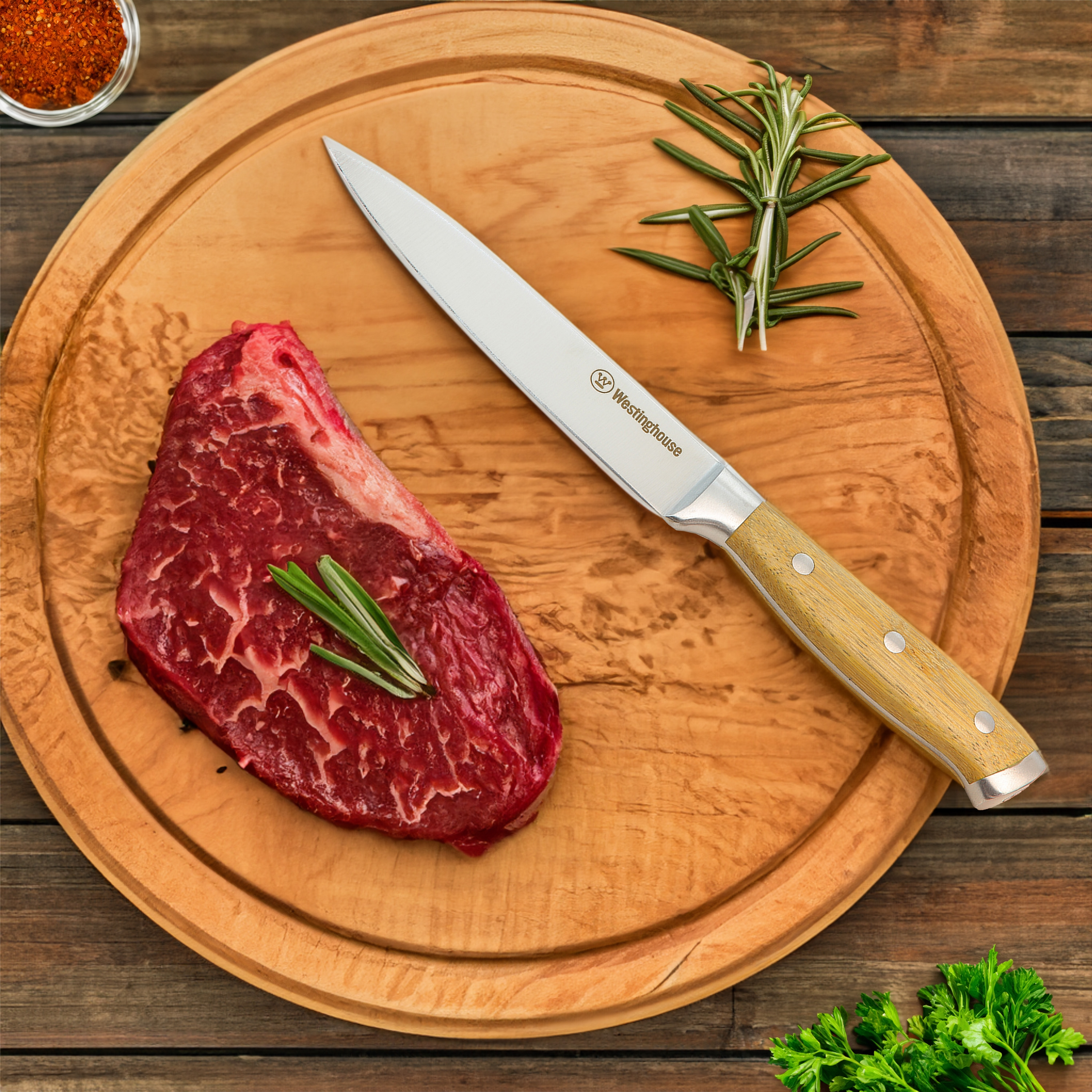 Rohes Steak und ein Messer auf einem hölzernen Schneidebrett. Rosmarin und Gewürze sind ebenfalls sichtbar.
