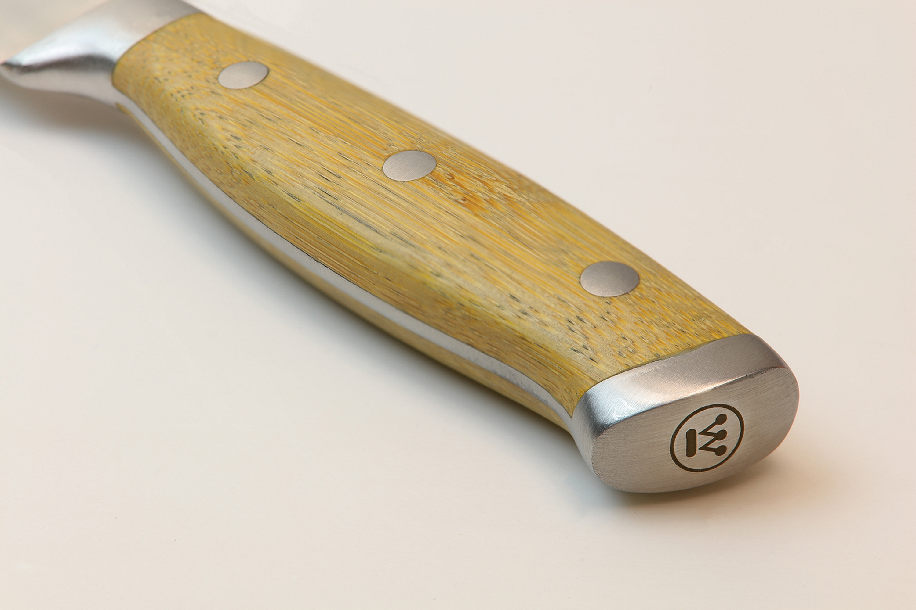 Nahaufnahme eines Messergriffs. Er besteht aus hellbraunem Holz mit silbernen Metallakzenten.