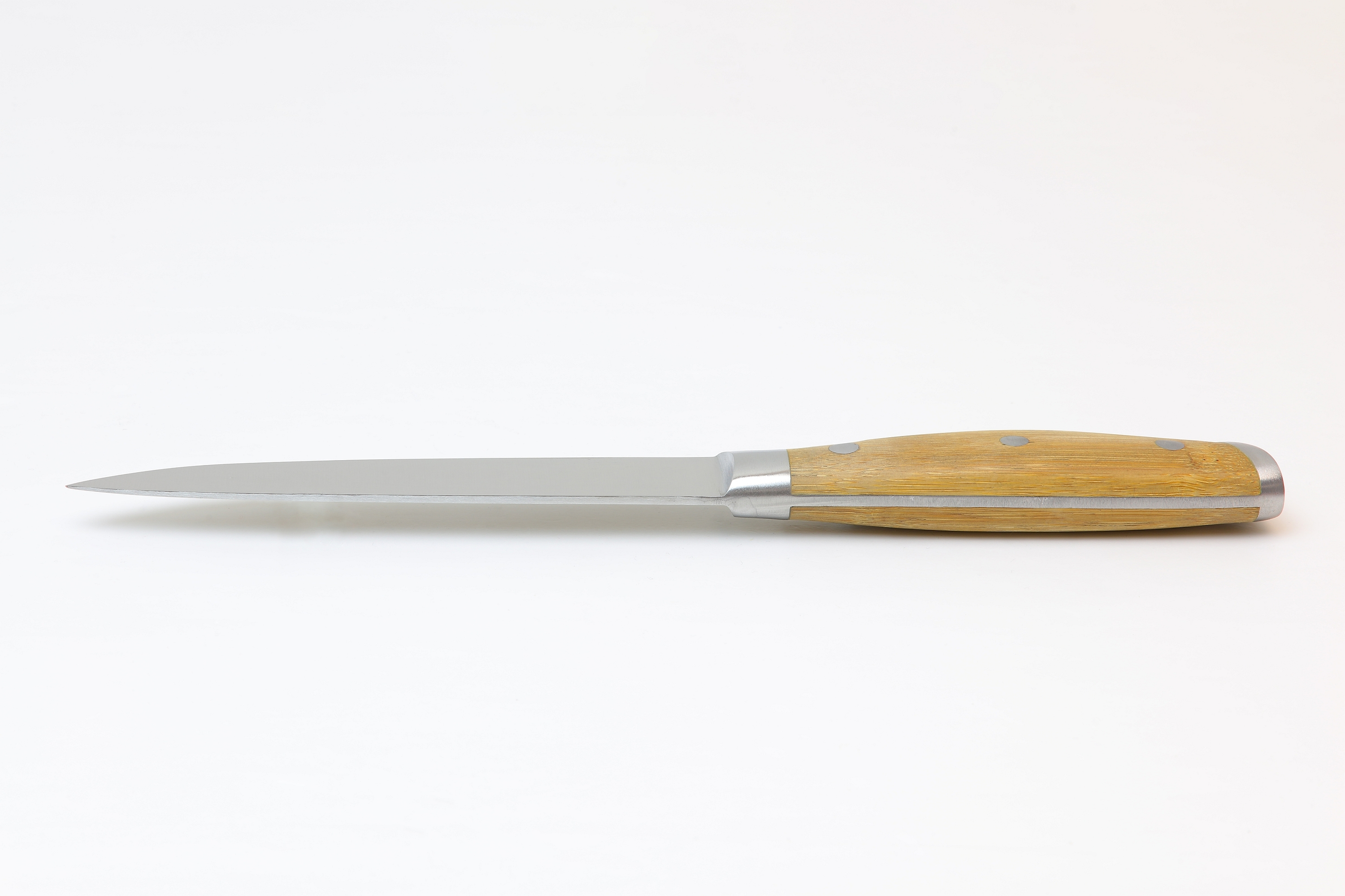Ein langes, dünnes Silbermesser mit Holzgriff liegt auf einer weißen Oberfläche.
