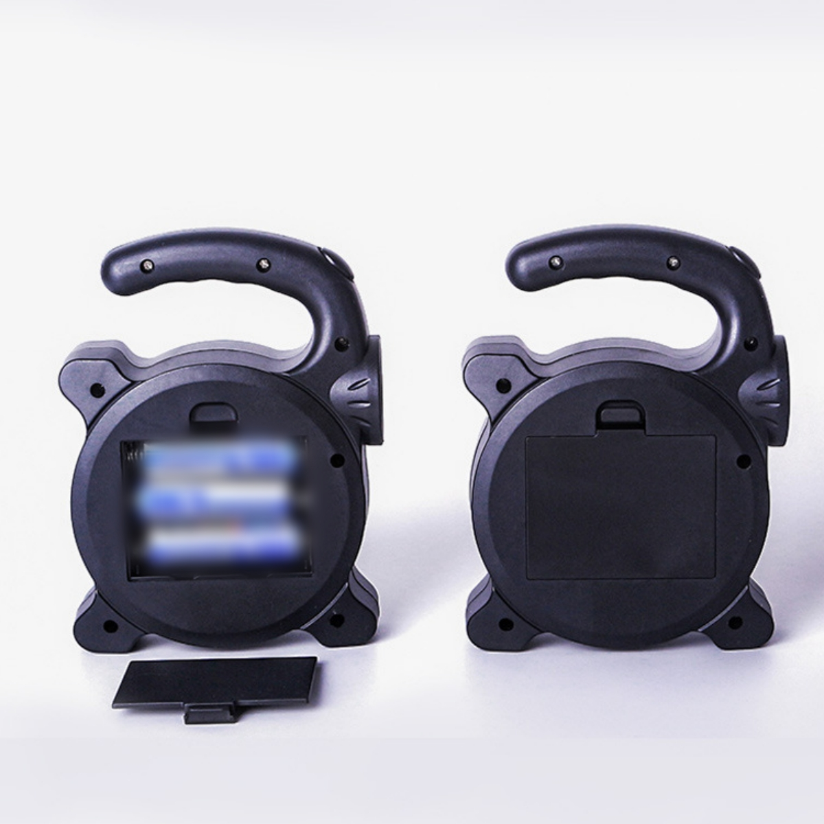 Zwei schwarze Laternen, die das offene Batteriefach zeigen. Die Batterie ist verschwommen.