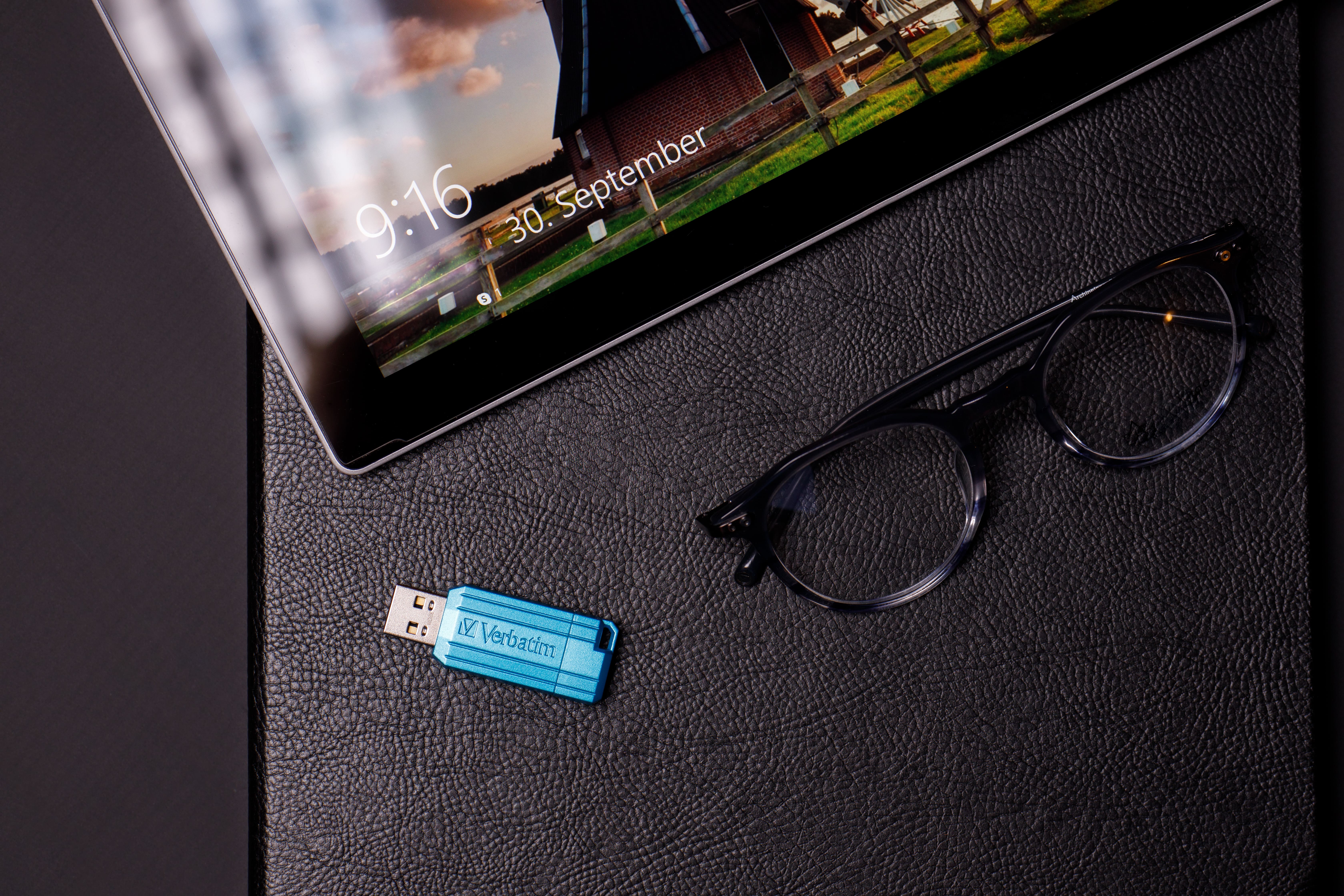 Tablet, Brille und blauer USB-Stick auf Leder. Tablet zeigt 9:16, 30. Sept.