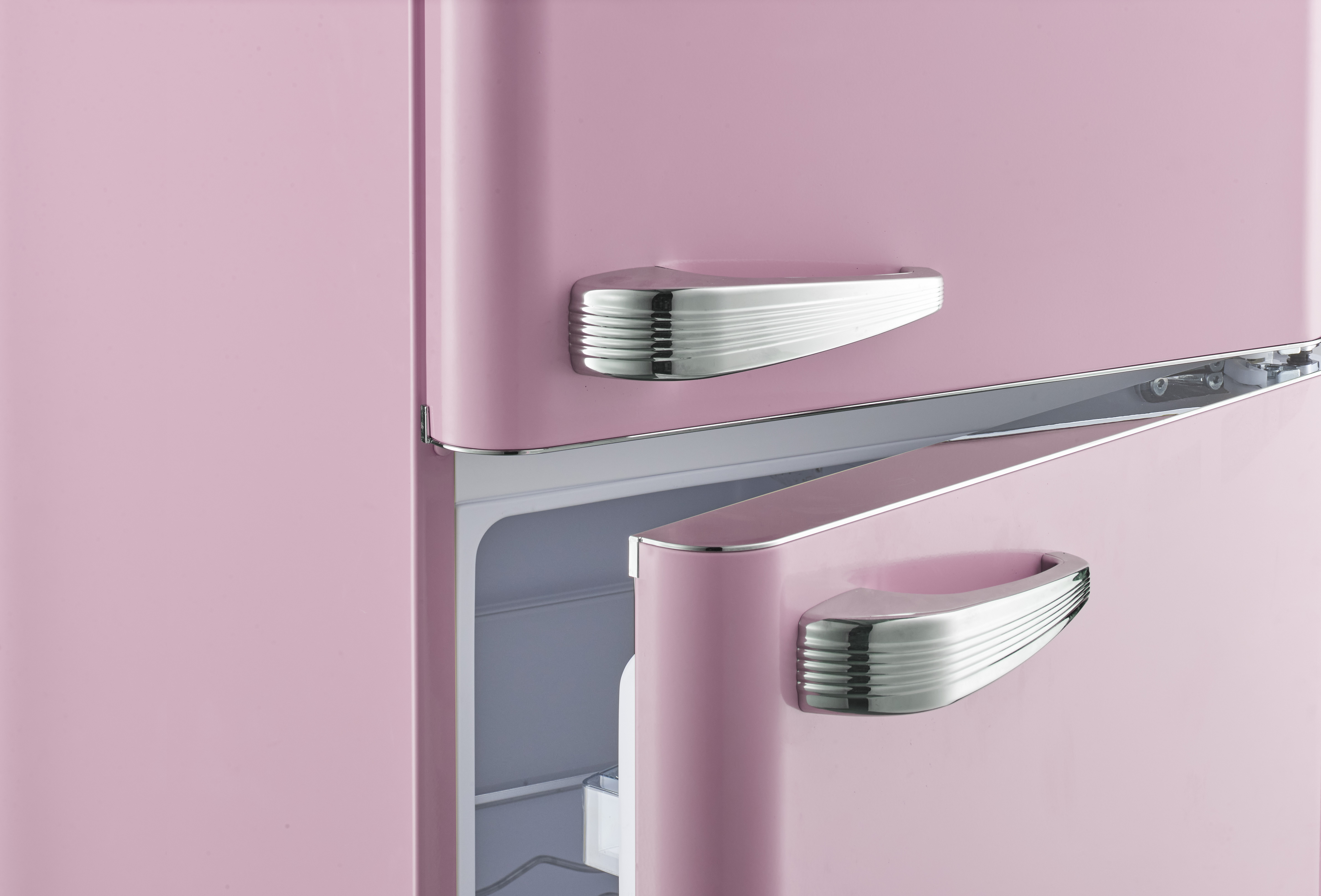 Rosa Retro-Kühlschrank mit Chromgriffen. Eine Tür ist teilweise geöffnet.