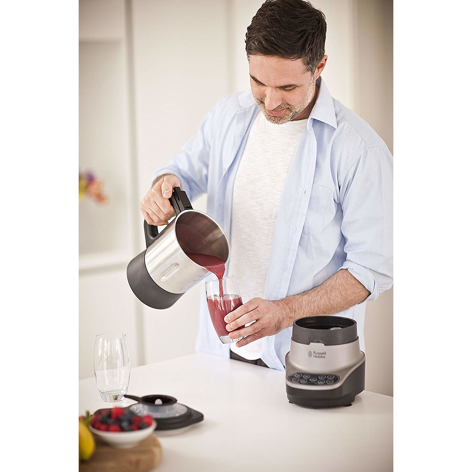 Un homme versant un liquide rouge d'un mixeur dans un verre.