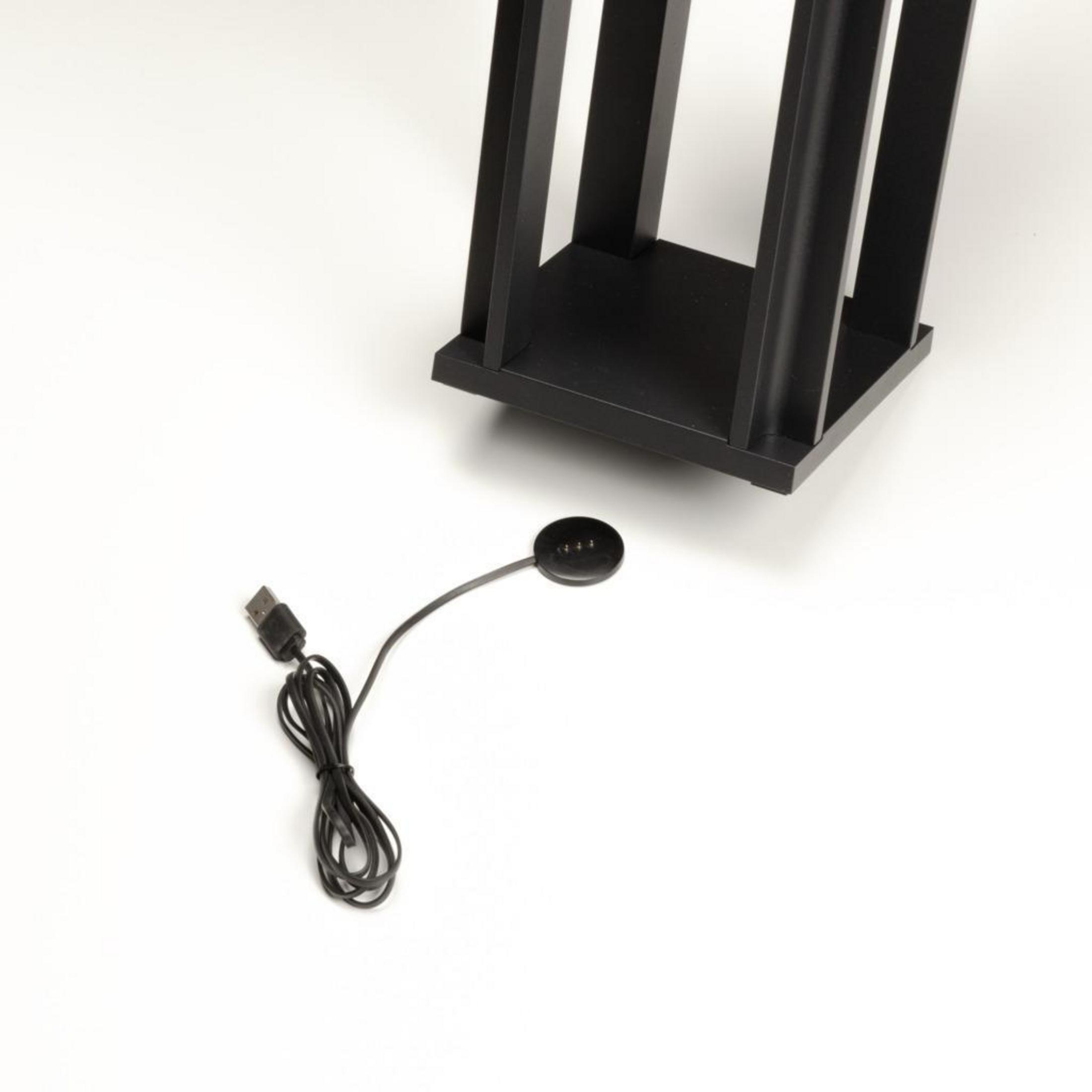 Schwarzer Ständer mit Ladekabel auf weißer Oberfläche.