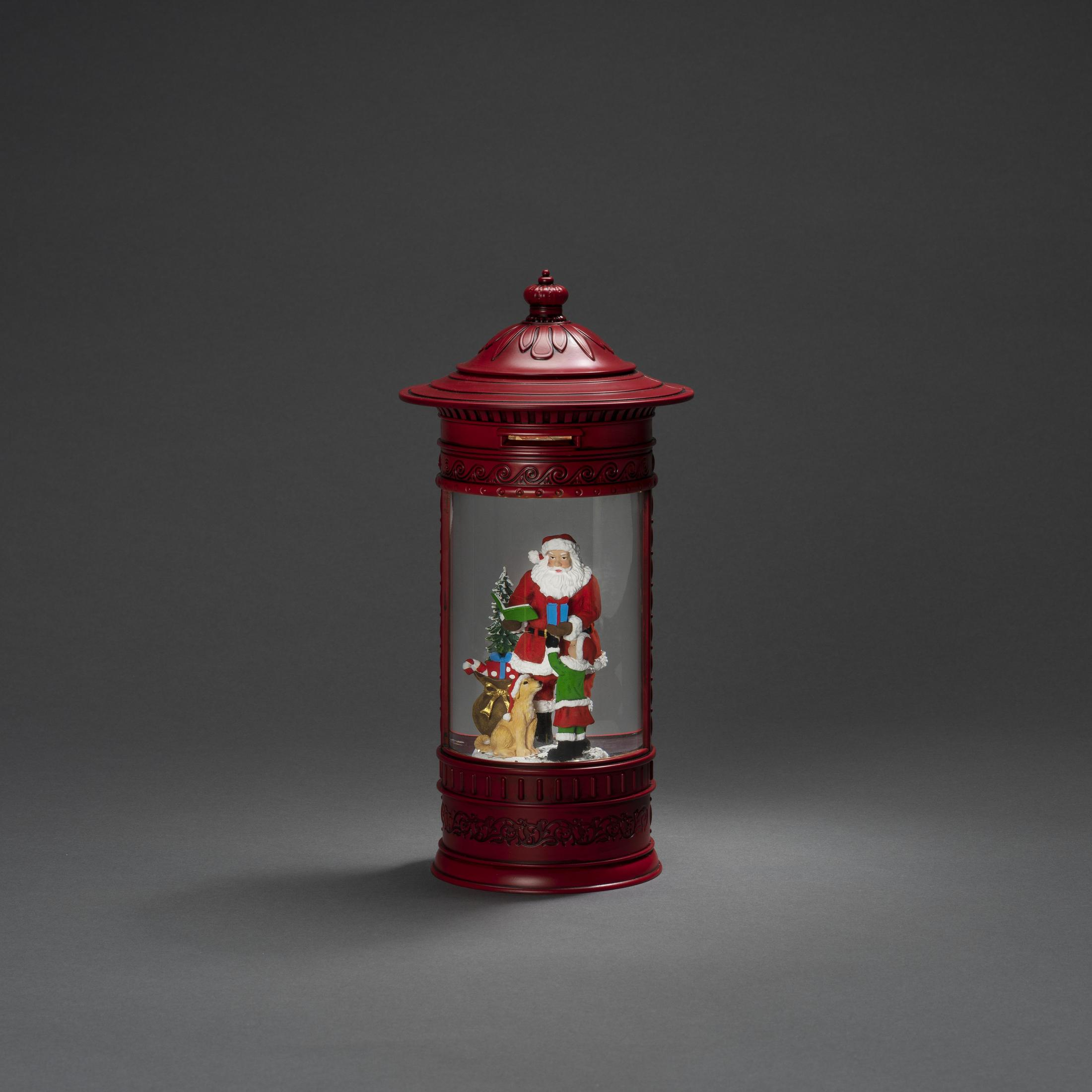 Eine rote Weihnachtslaterne mit einer Weihnachtsmann- und Rentierszene im Inneren, auf grauem Hintergrund.