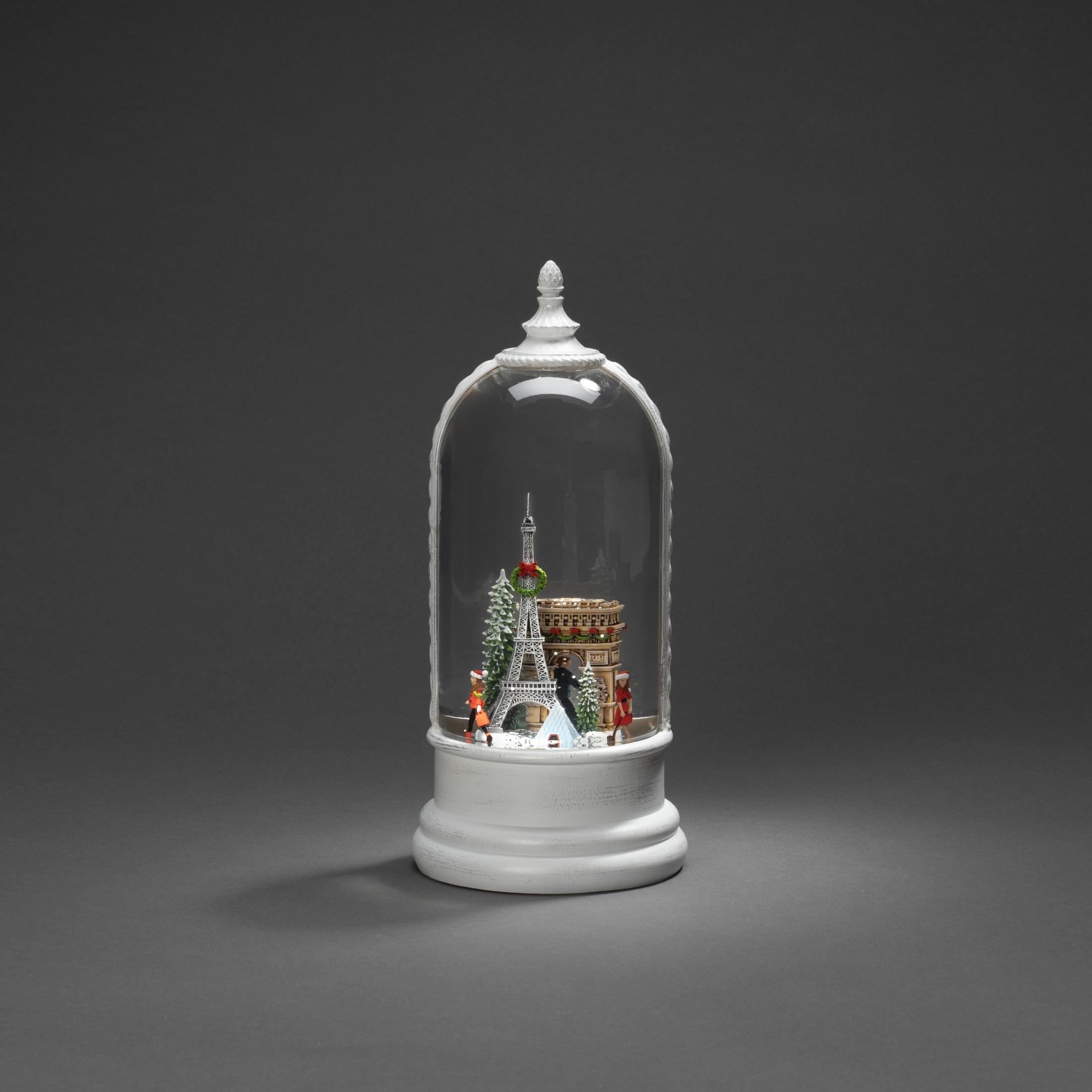 Eine Schneekugel mit Miniatur-Eiffelturm und anderen Sehenswürdigkeiten auf grauer Oberfläche.