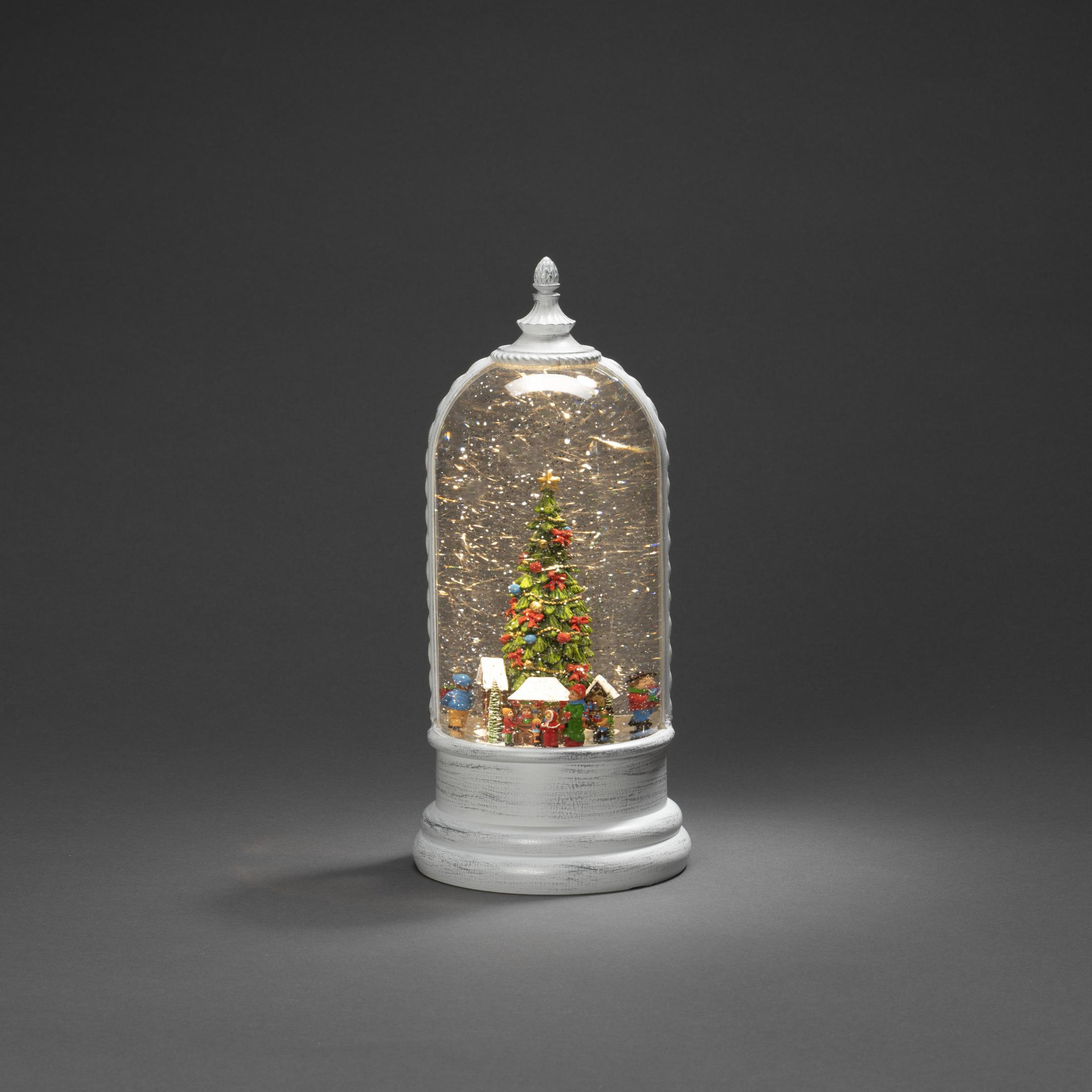Eine Schneekugel zeigt einen Weihnachtsbaum, kleine Häuser und Figuren in einer Glaskuppel.