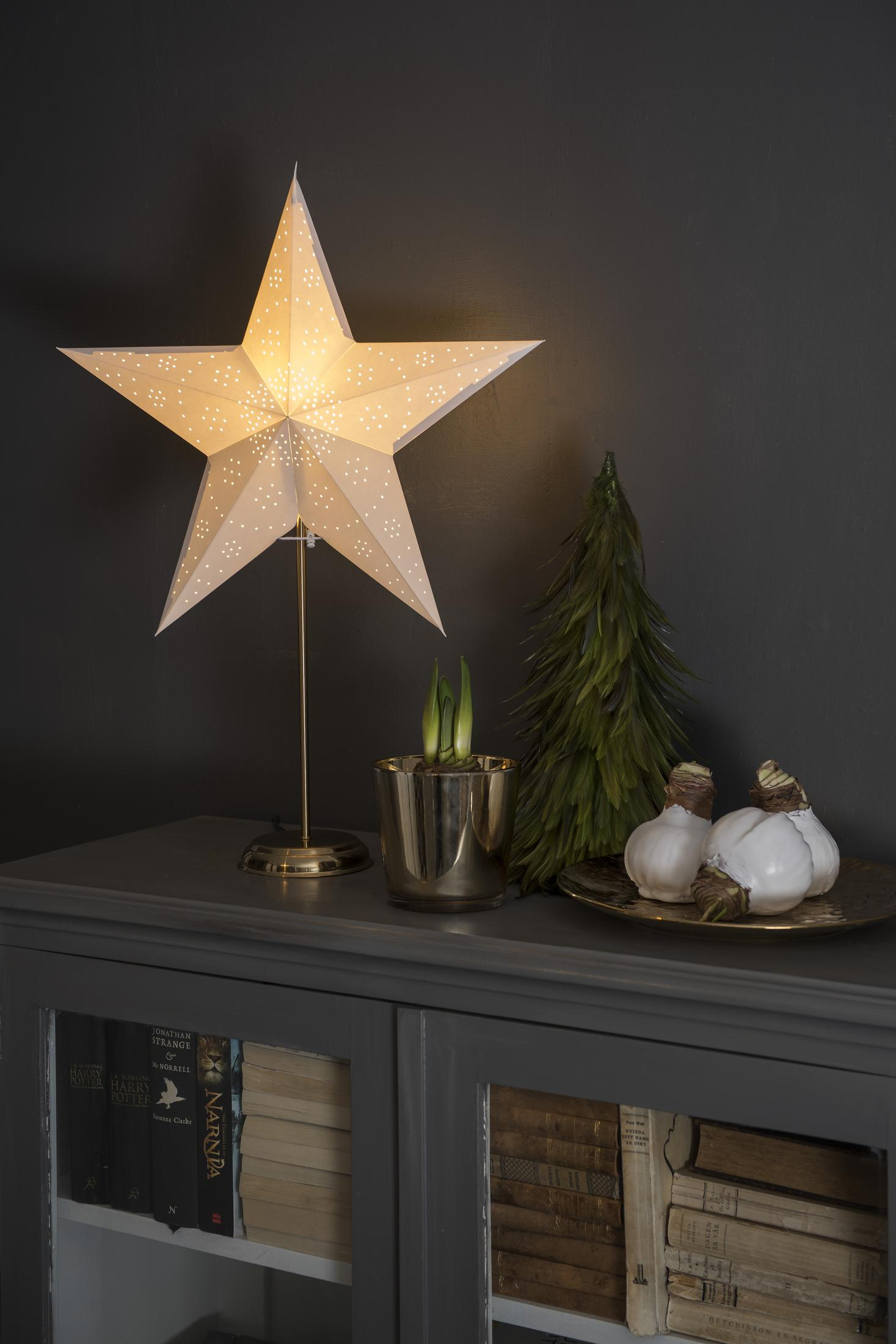 Una lampada a forma di stella illuminata su un mobile con decorazioni.