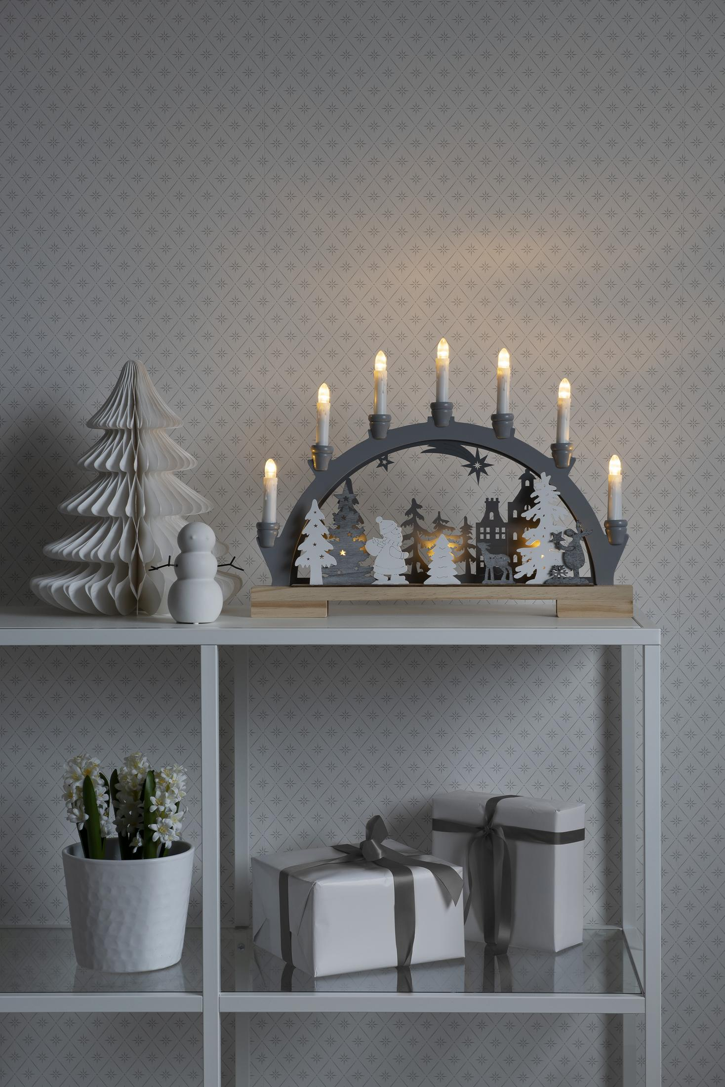 Weihnachtsszene mit dekorativem Bogen mit Kerzen, Papiertanne und Geschenken.