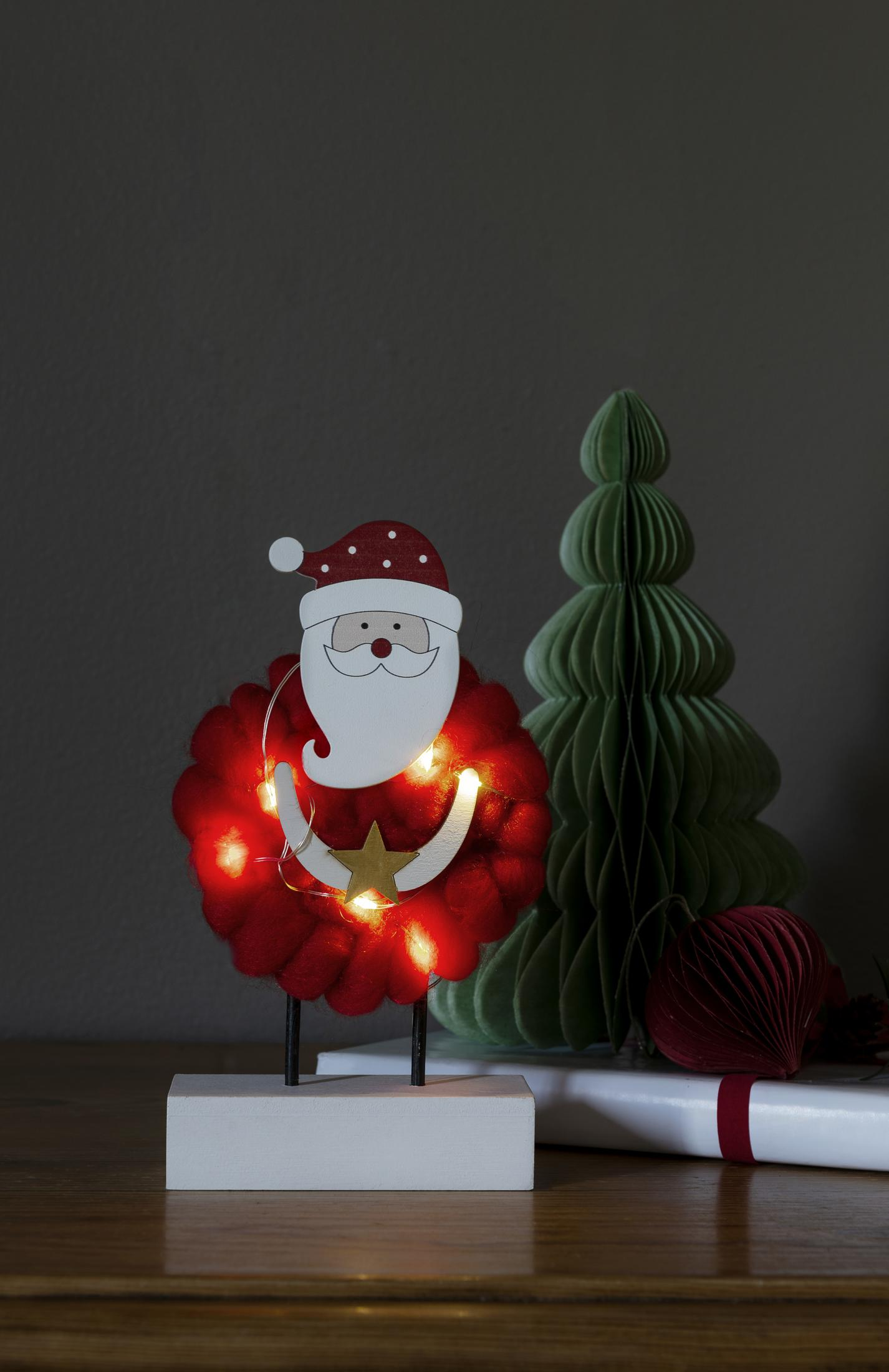 Eine Holz-Weihnachtsdekoration mit Lichtern und ein Papier-Weihnachtsbaum stehen auf einem Tisch.