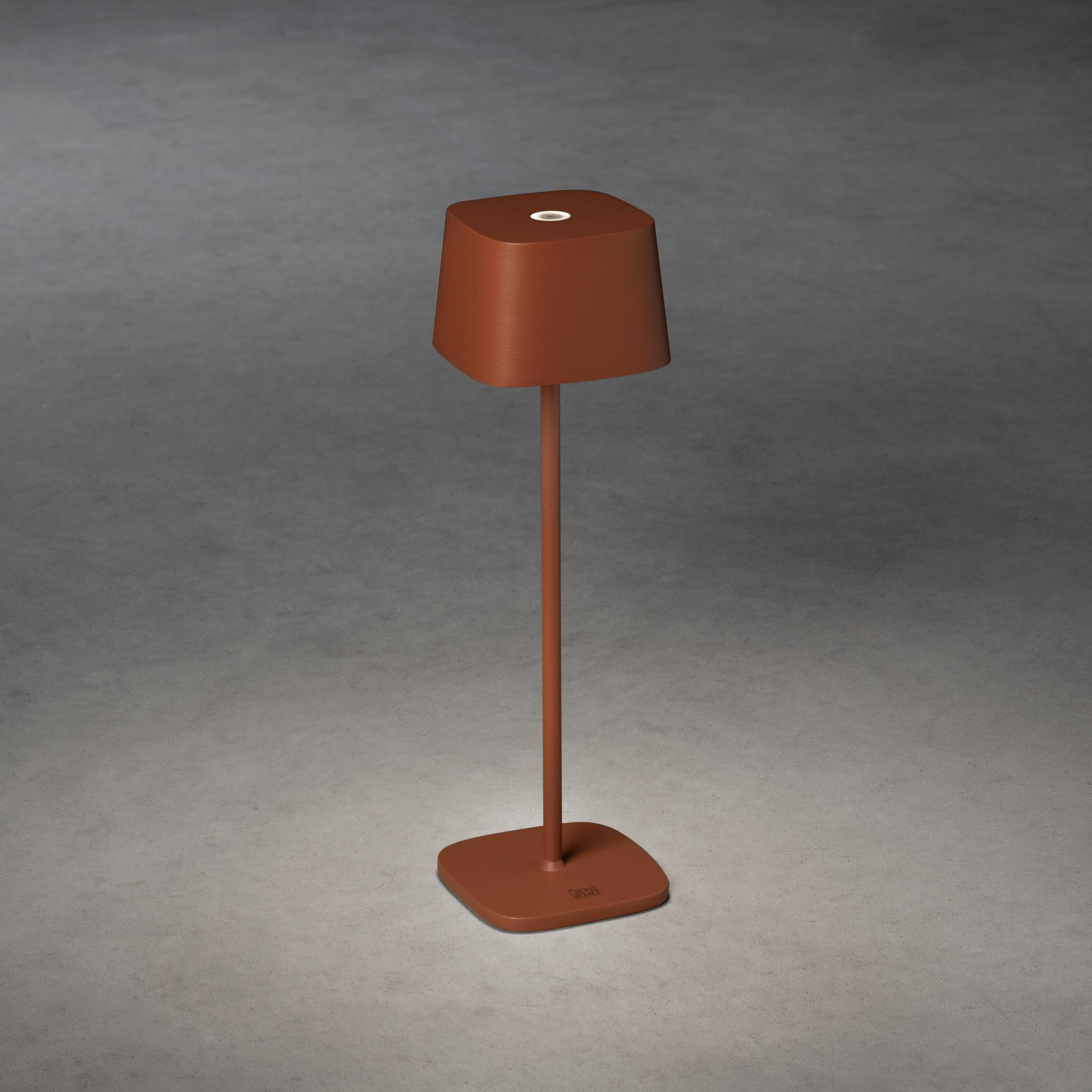 Eine braune, modern aussehende Lampe auf einem quadratischen Sockel. Sie hat einen quadratischen Lampenschirm und einen dünnen Stiel.