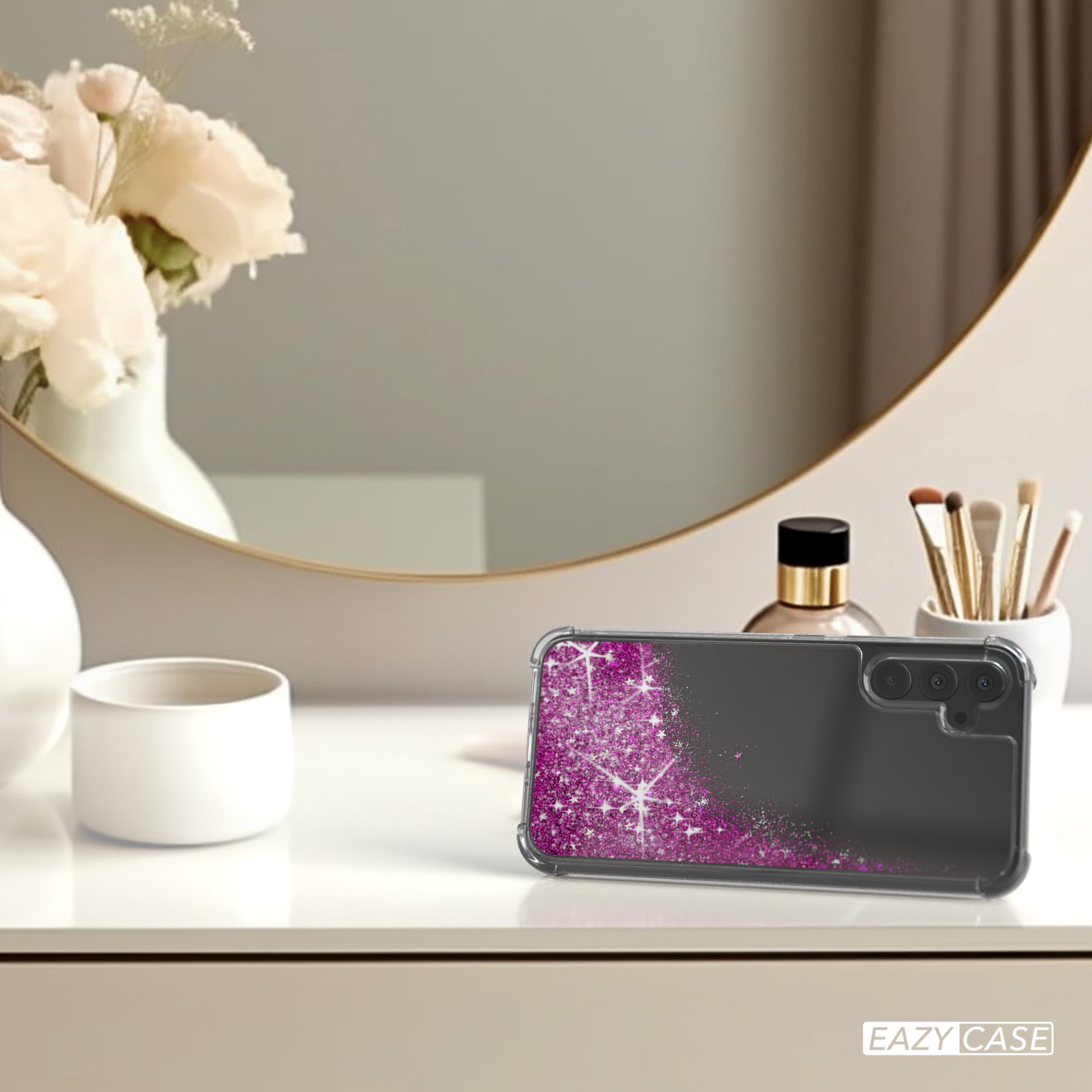 Handyhülle mit rosa Glitzer, auf Tisch mit Spiegel und Blumen.