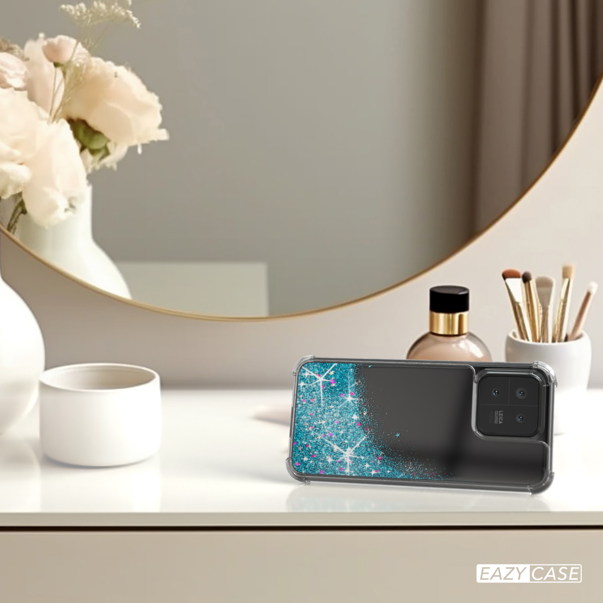 Handyhülle mit Glitzerdesign auf einem Tisch. Im Hintergrund Spiegel und Kosmetika.