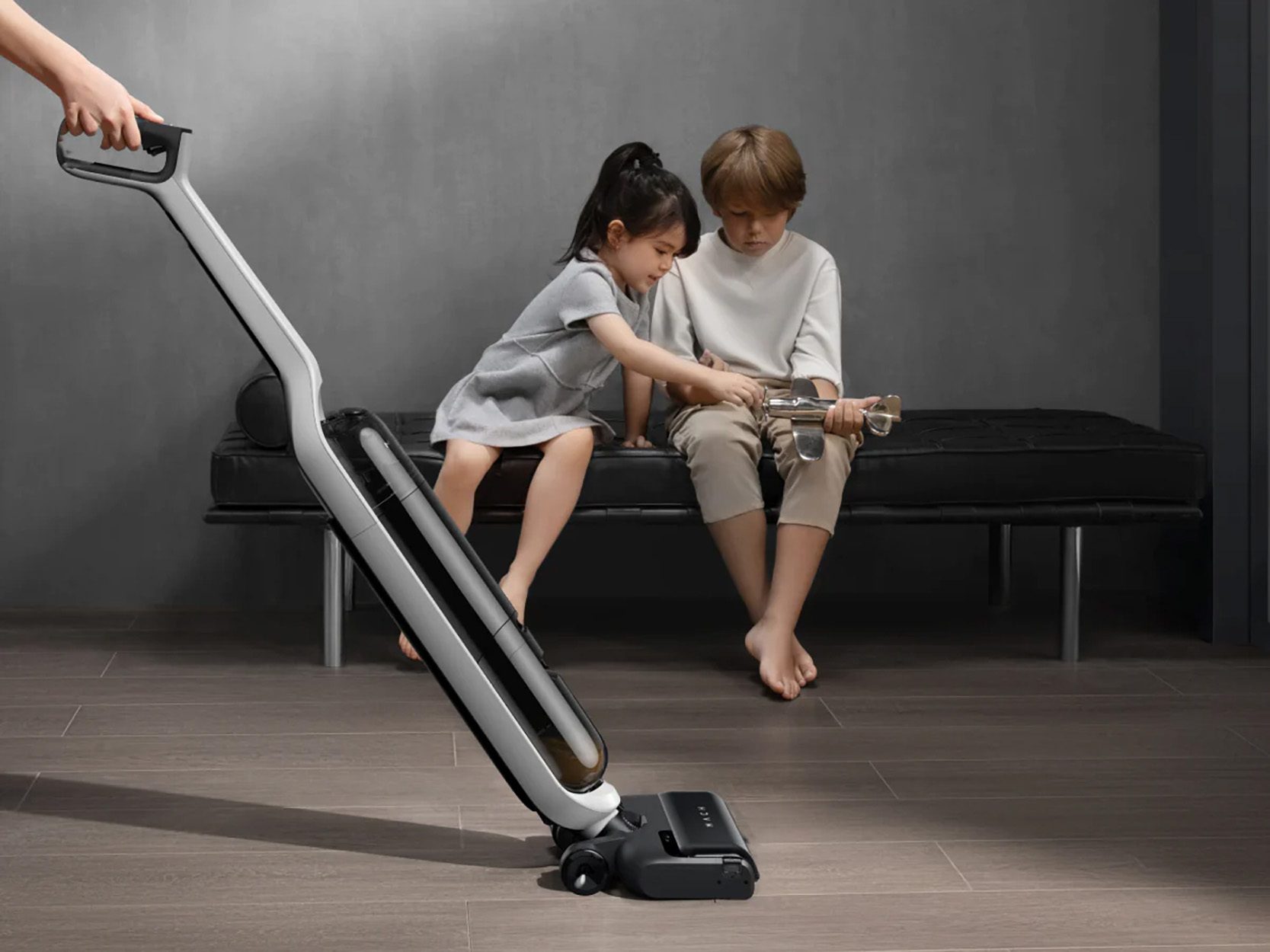 Twee kinderen spelen met een stofzuiger. Eén houdt de hendel vast.