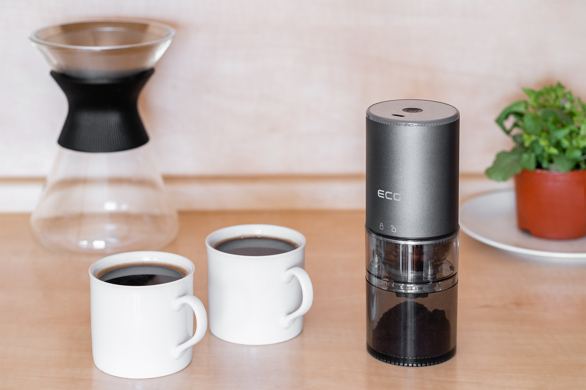 Kaffeezubereitung: Mahlwerk, zwei Kaffeetassen, Pour-Over und Pflanze. Alles auf Holz.
