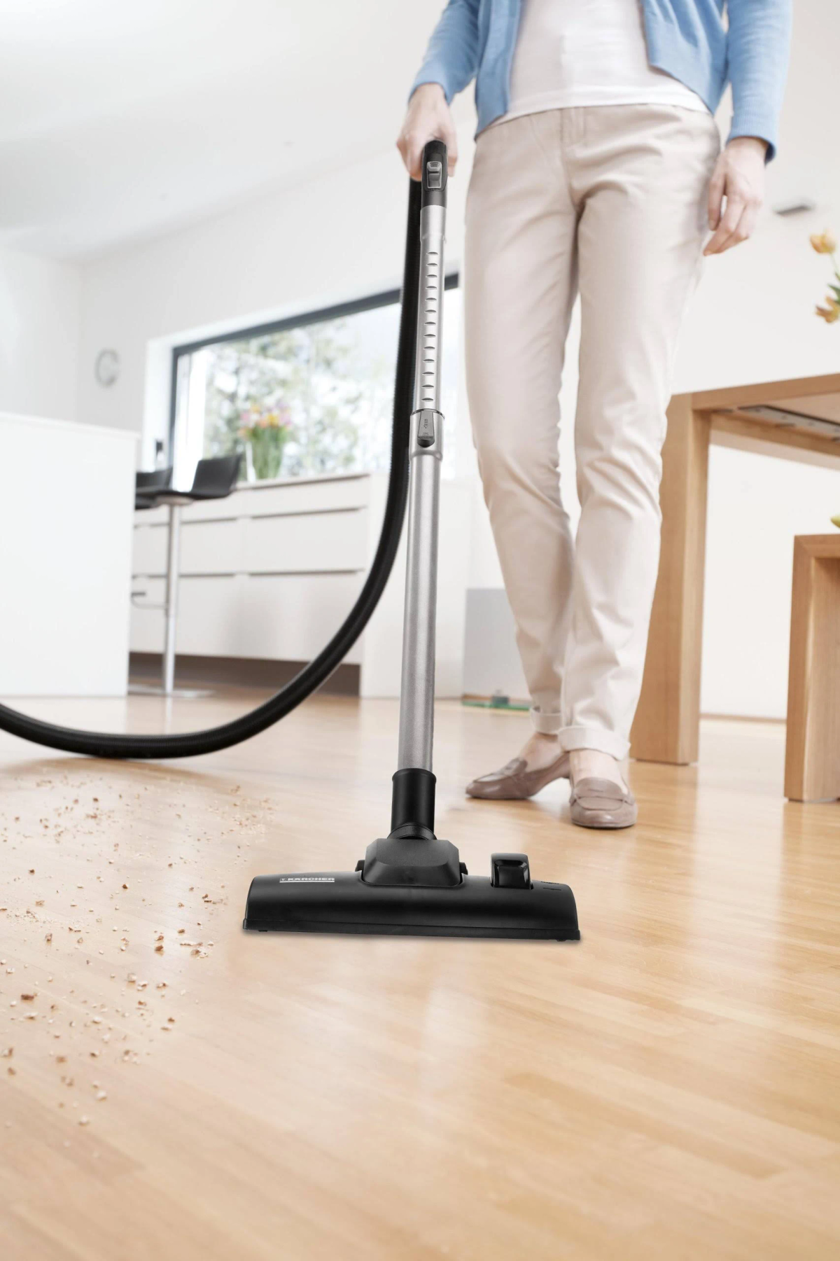 Una persona che aspira un pavimento in legno con un'aspirapolvere Kärcher.