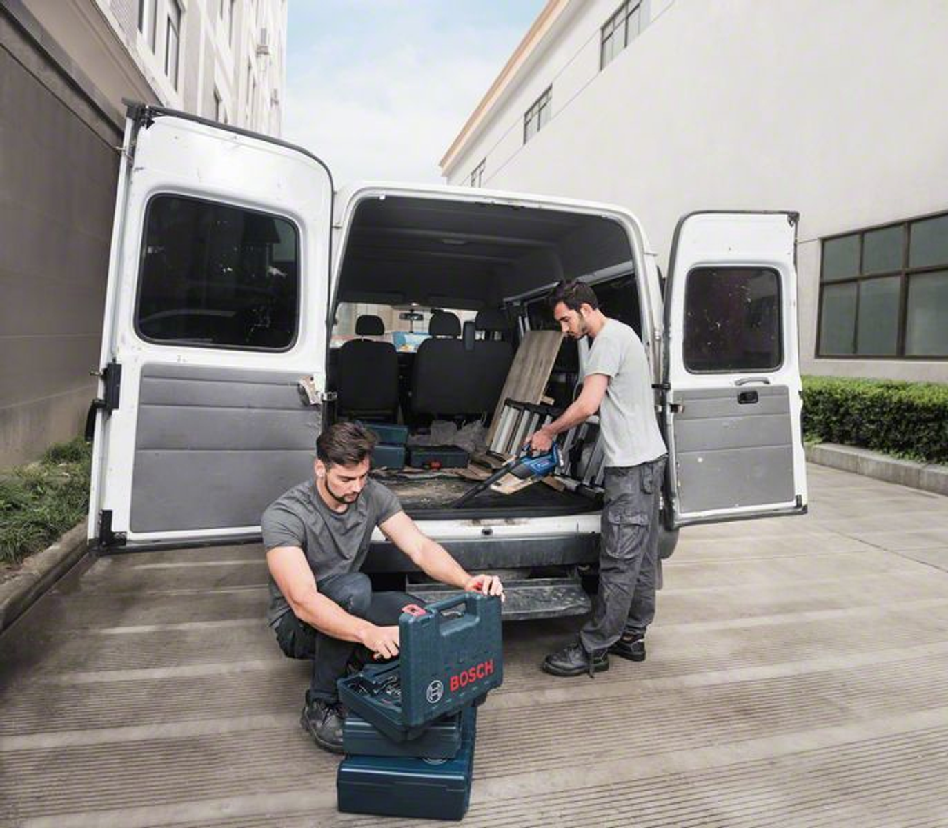 Dwóch mężczyzn ładuje pudła do vana z otwartymi drzwiami.