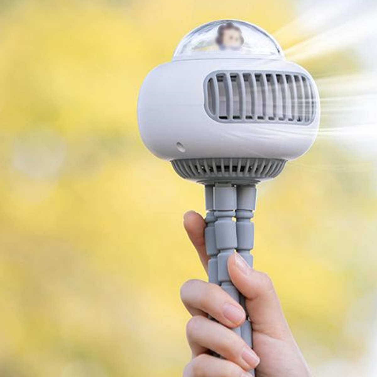 Weißer Ventilator an einer Hand befestigt, unscharfer Hintergrund.