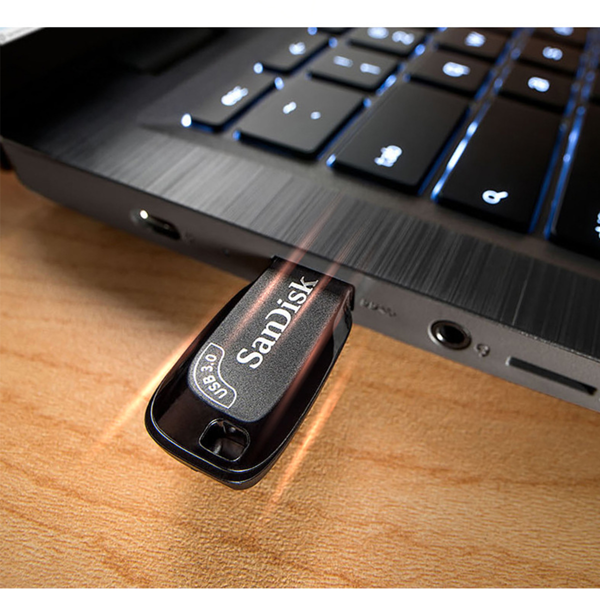 Schwarzer USB-Stick, der teilweise in einen Laptop eingesteckt ist. Auf dem Stick steht 'SanDisk' und 'USB 3.0'.