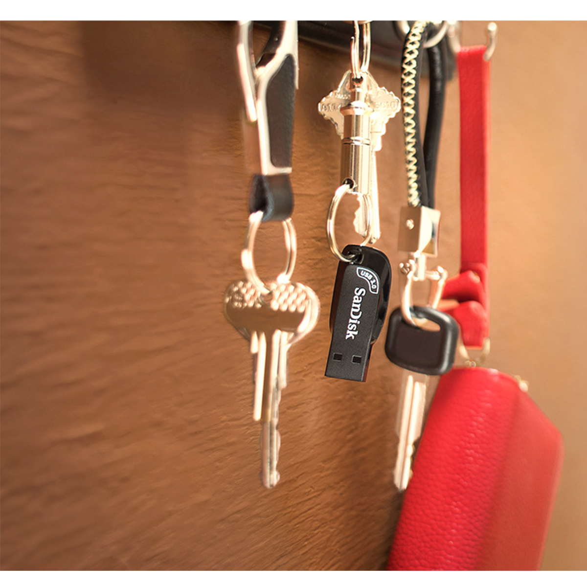 Schlüssel, die an einem Haken hängen, einschließlich eines Schlüssels mit einem Sandisk USB-Laufwerk.