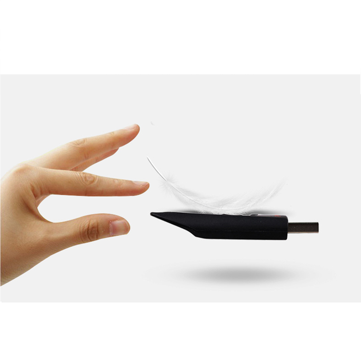 Eine Hand, die sich einer Feder nähert, die über einem schwarzen USB-Gerät schwebt.