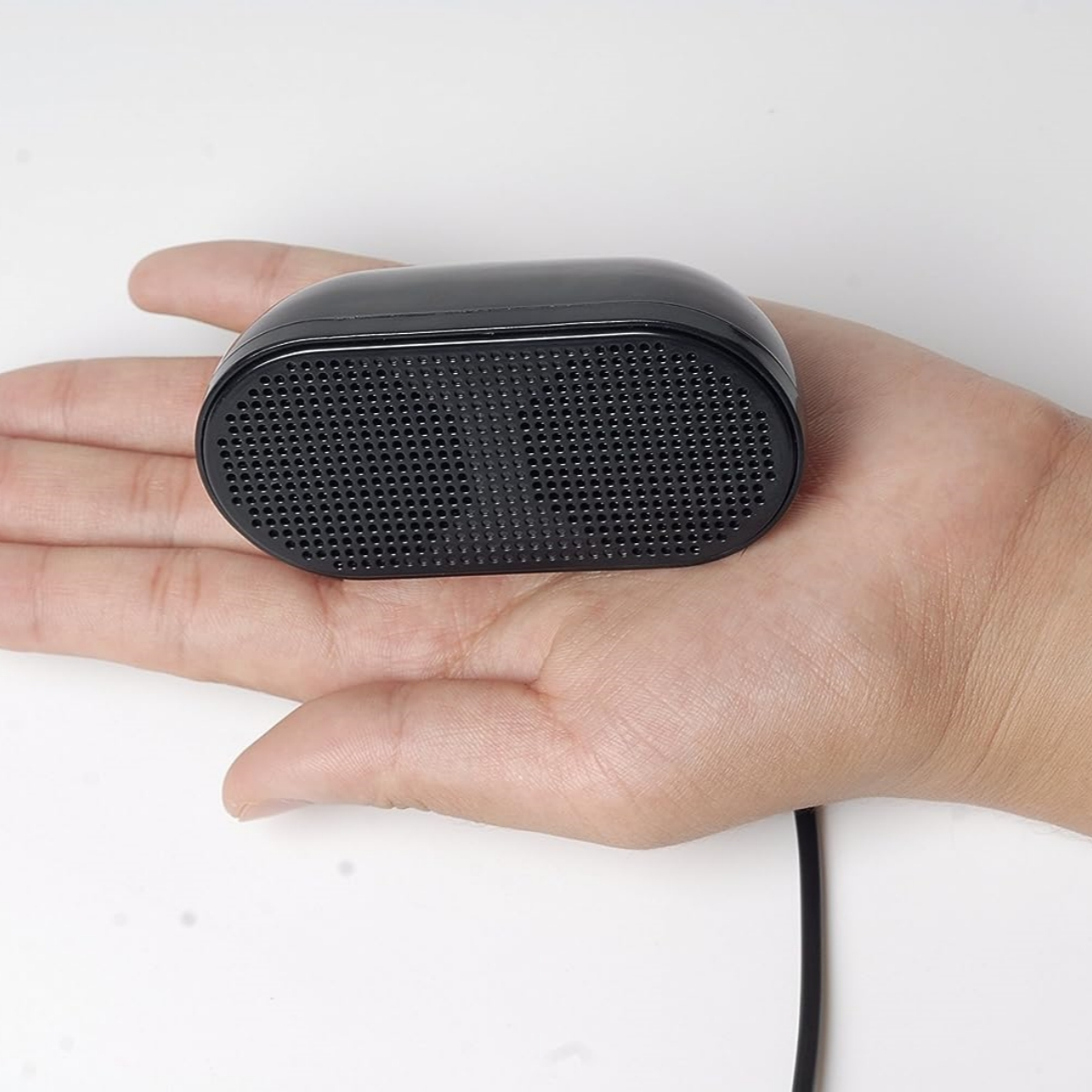 Schwarzer Lautsprecher in der Handfläche einer Person, mit schwarzem Kabel.