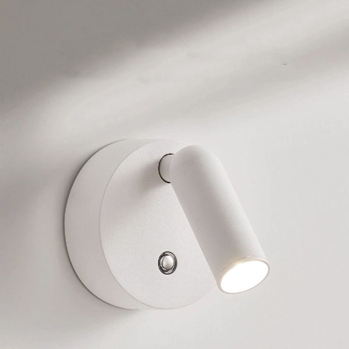 Weiße Wandleuchte mit zylindrischem Kopf, schlichtes Design.