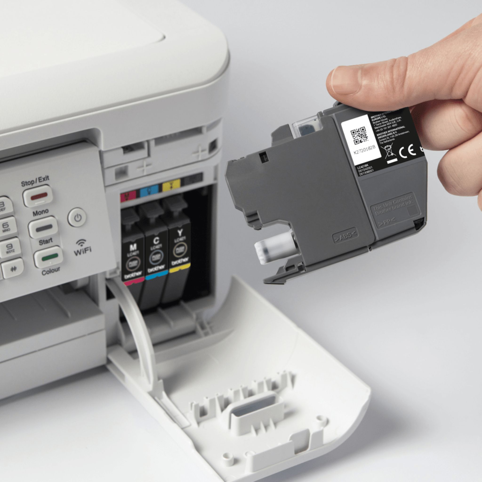 A person inserting a black ink cartridge into a white inkjet printer. Close-up.