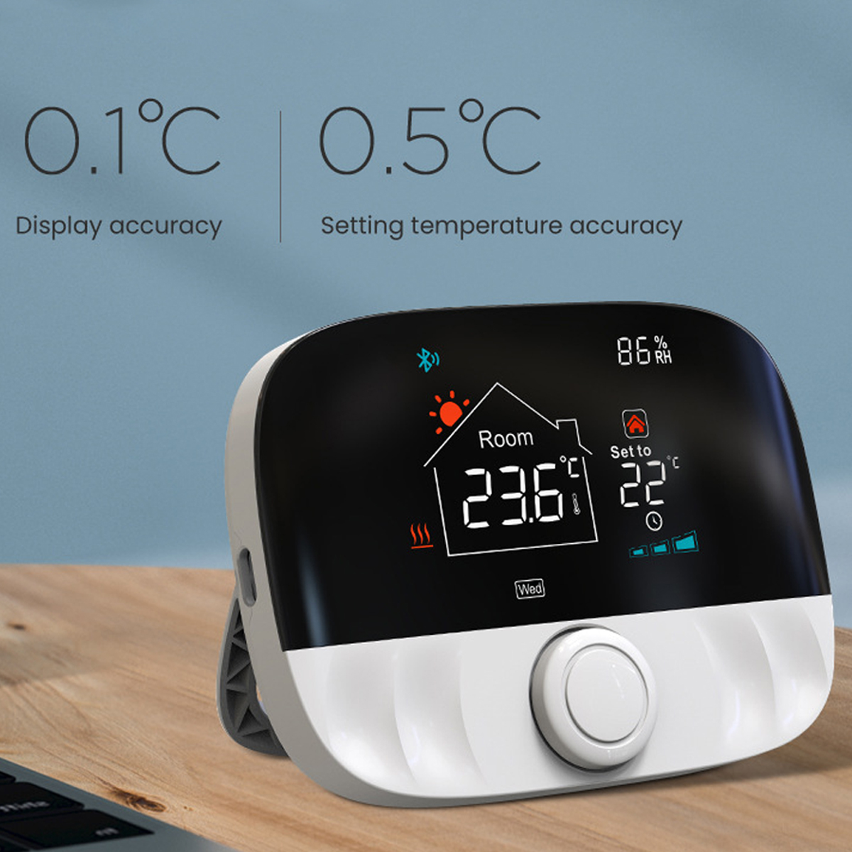 Ein weißes und graues Smart-Thermostat, das die Raumtemperatur und die Solltemperatur anzeigt. Es steht auf einem Holztisch.