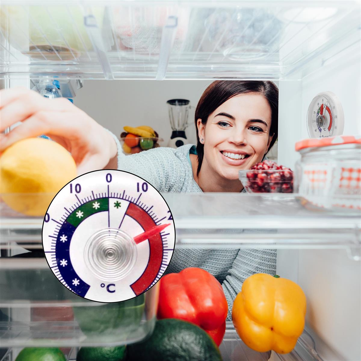 Eine lächelnde Frau greift in einen Kühlschrank mit Früchten, ein Thermometer ist sichtbar.
