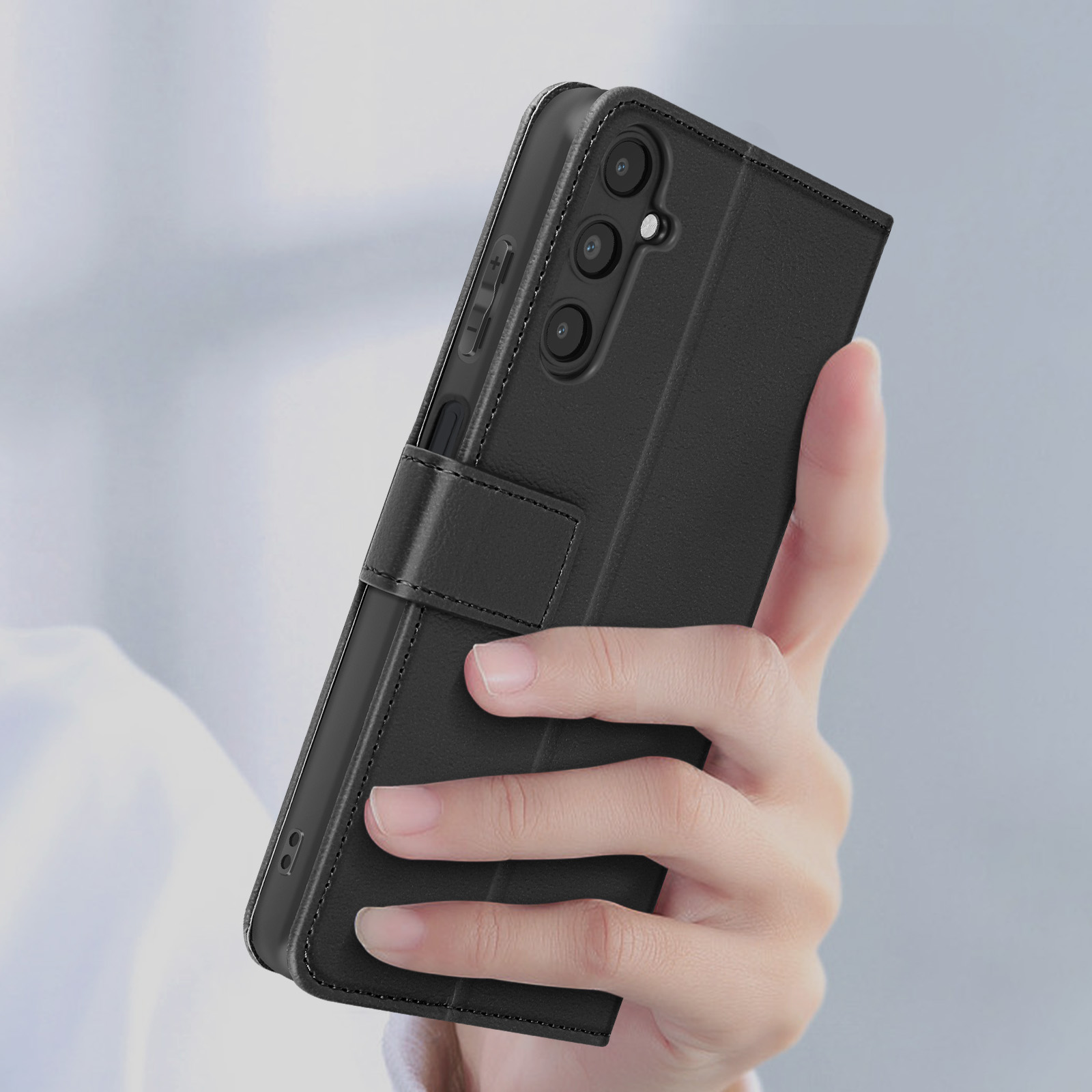 Mano che tiene una custodia per telefono nera con design a portafoglio. Ha una chiusura.