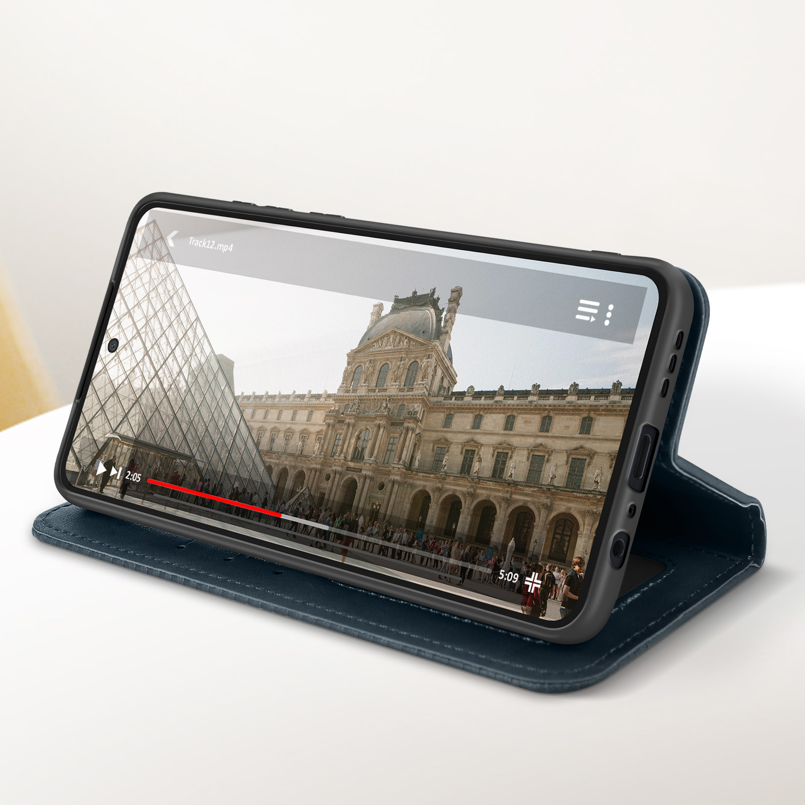 Smartphone in custodia blu che mostra un video sullo schermo con lo sfondo del Louvre.