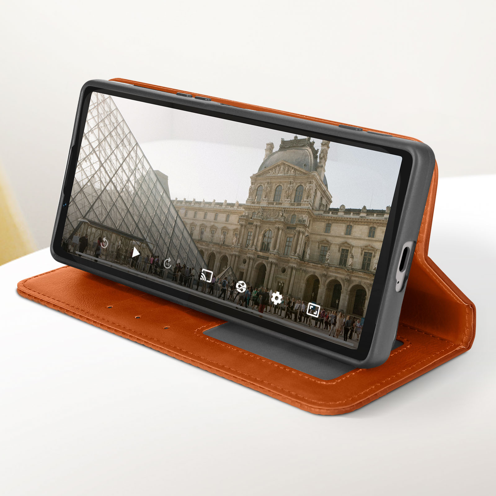 Tablet in una custodia in pelle marrone, mostra un edificio con persone. Appoggiato alla custodia.