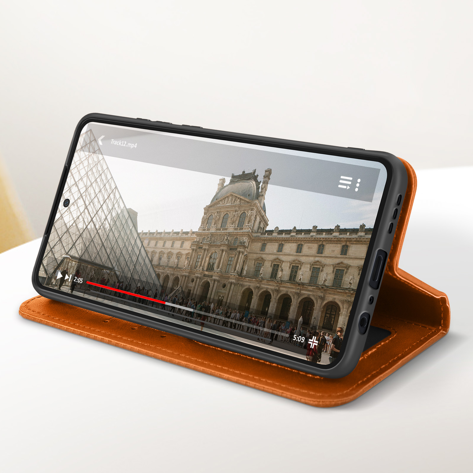 Custodia arancione con telefono che mostra un video del Museo del Louvre. Interno visibile.