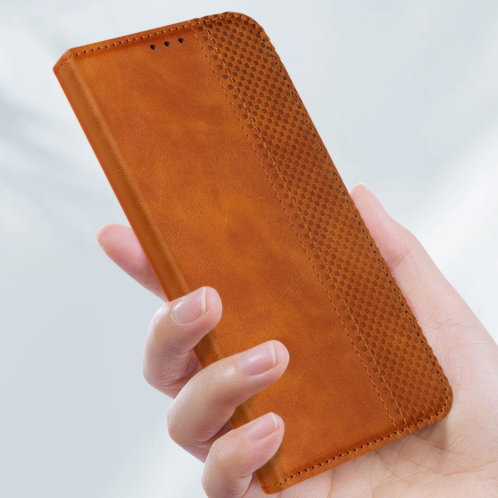Una mano che tiene una custodia per telefono in pelle marrone. La custodia ha un design strutturato.