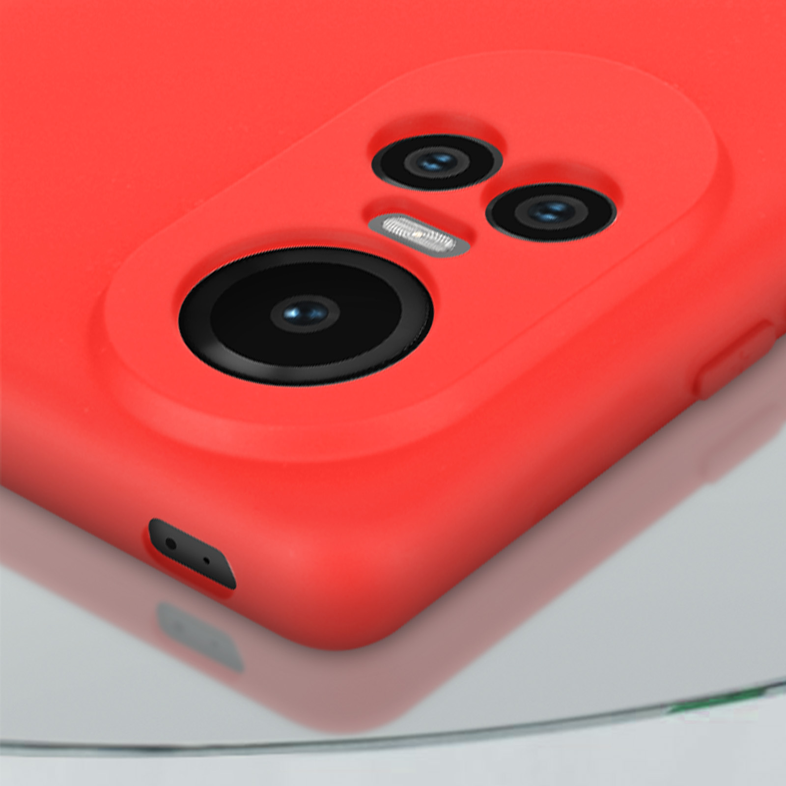 Custodia rossa per telefono con tre obiettivi, primo piano su superficie riflettente.