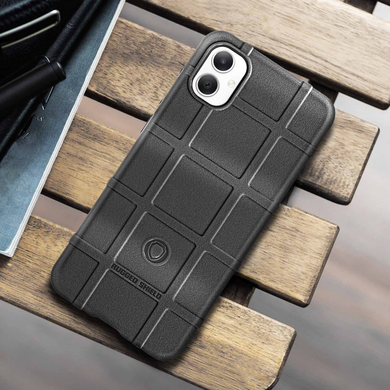 Una custodia per telefono nera con un motivo a griglia strutturata è posizionata su un tavolo di legno.